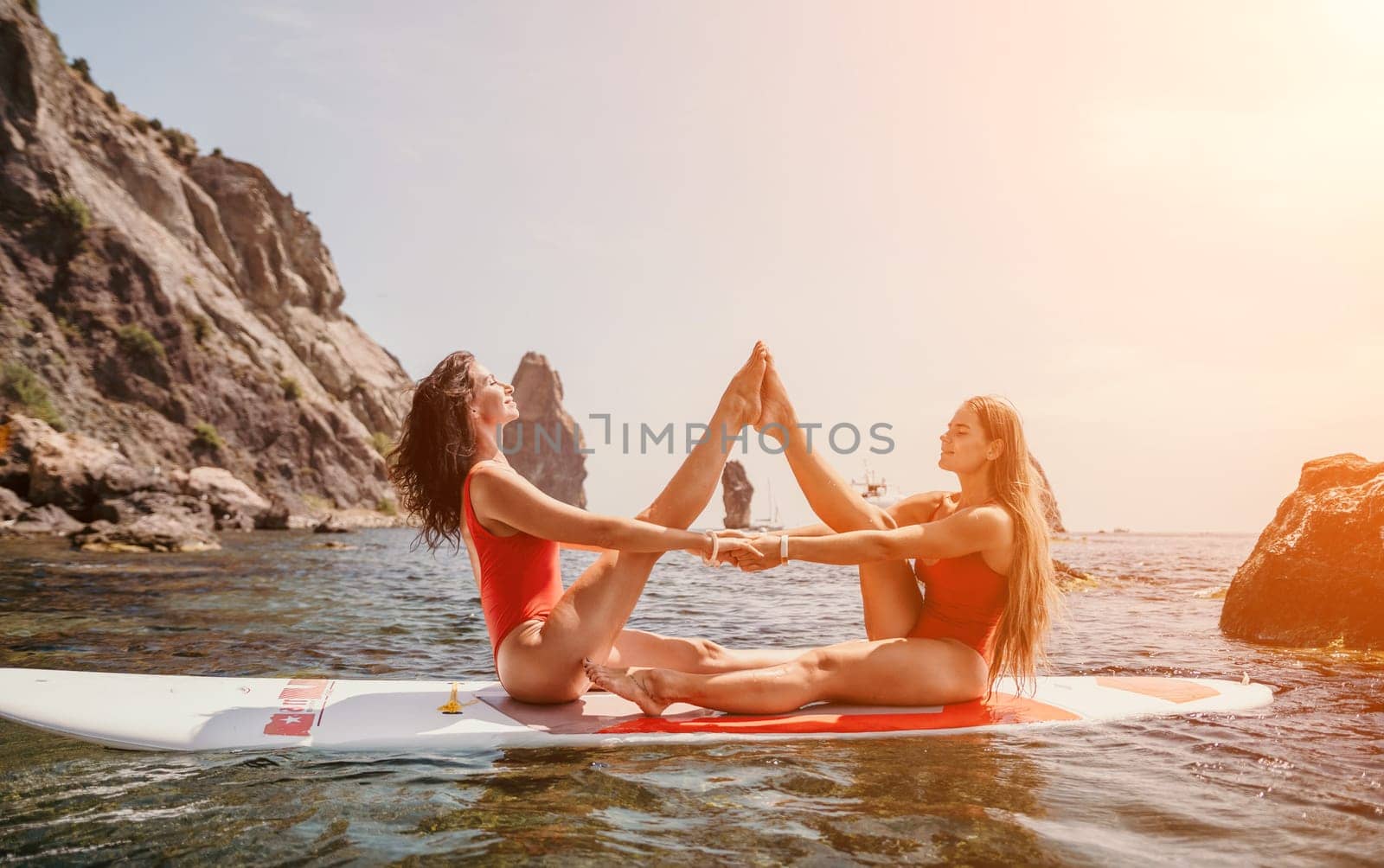 Woman sup yoga. Middle age sporty woman practising yoga pilates on paddle sup surfboard. Female stretching doing workout on sea water. Modern individual hipster outdoor summer sport activity