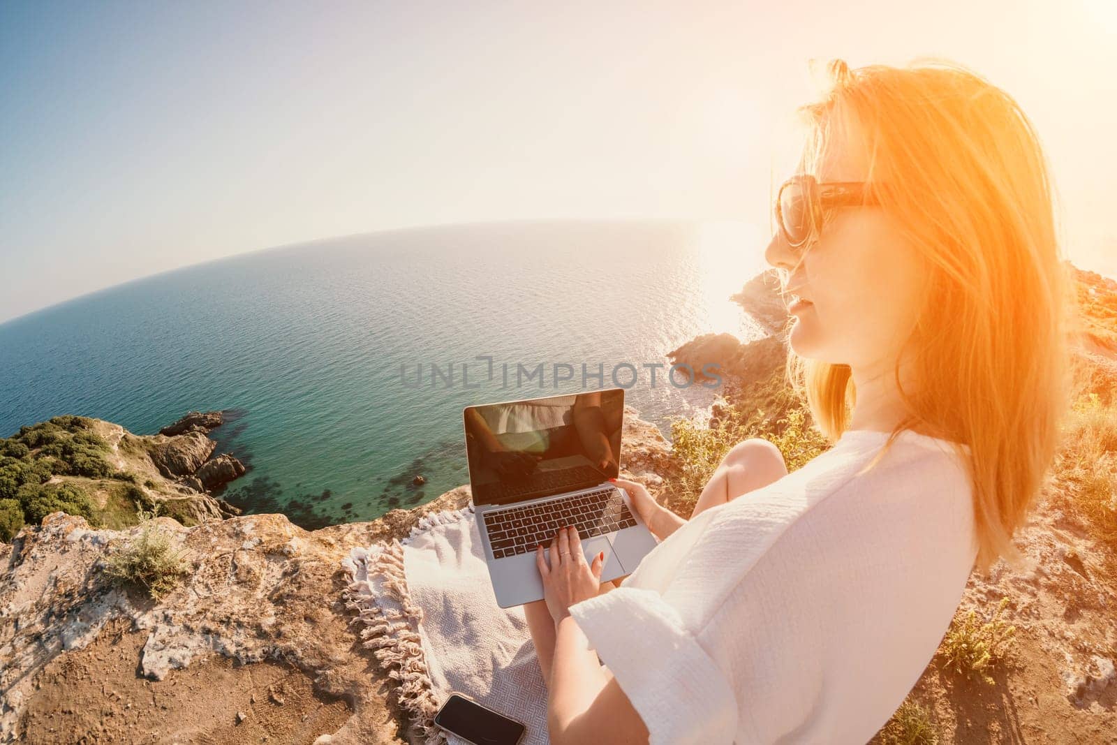 Woman sea laptop. Business woman in yellow hat working on laptop by sea. Close up on hands of pretty lady typing on computer outdoors summer day. Freelance, digital nomad, travel and holidays concept.