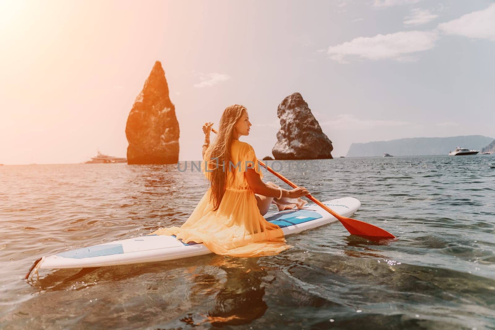 Close up shot of beautiful young caucasian woman with black hair and freckles looking at camera and smiling. Cute woman portrait in a pink bikini posing on a volcanic rock high above the sea