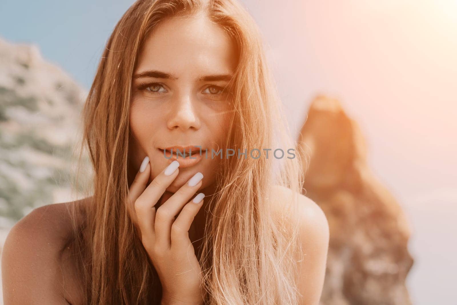 Woman travel sea. Young Happy woman in a long red dress posing on a beach near the sea on background of volcanic rocks, like in Iceland, sharing travel adventure journey