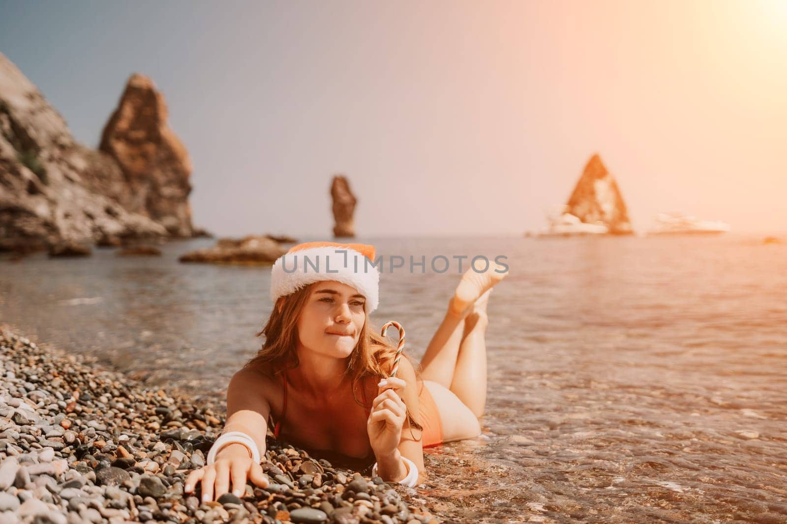 Woman travel sea. Happy tourist enjoy taking picture on the beach for memories. Woman traveler in Santa hat looks at camera on the sea bay, sharing travel adventure journey by panophotograph