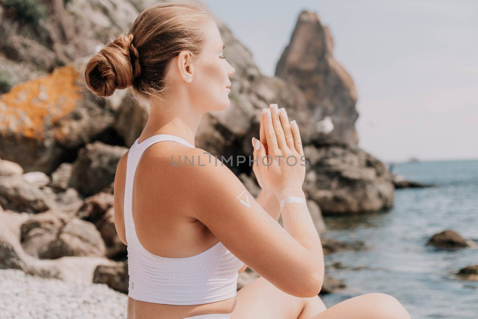 Woman sea yoga. Happy women meditating in yoga pose on the beach, ocean and rock mountains. Motivation and inspirational fit and exercising. Healthy lifestyle outdoors in nature, fitness concept. by panophotograph