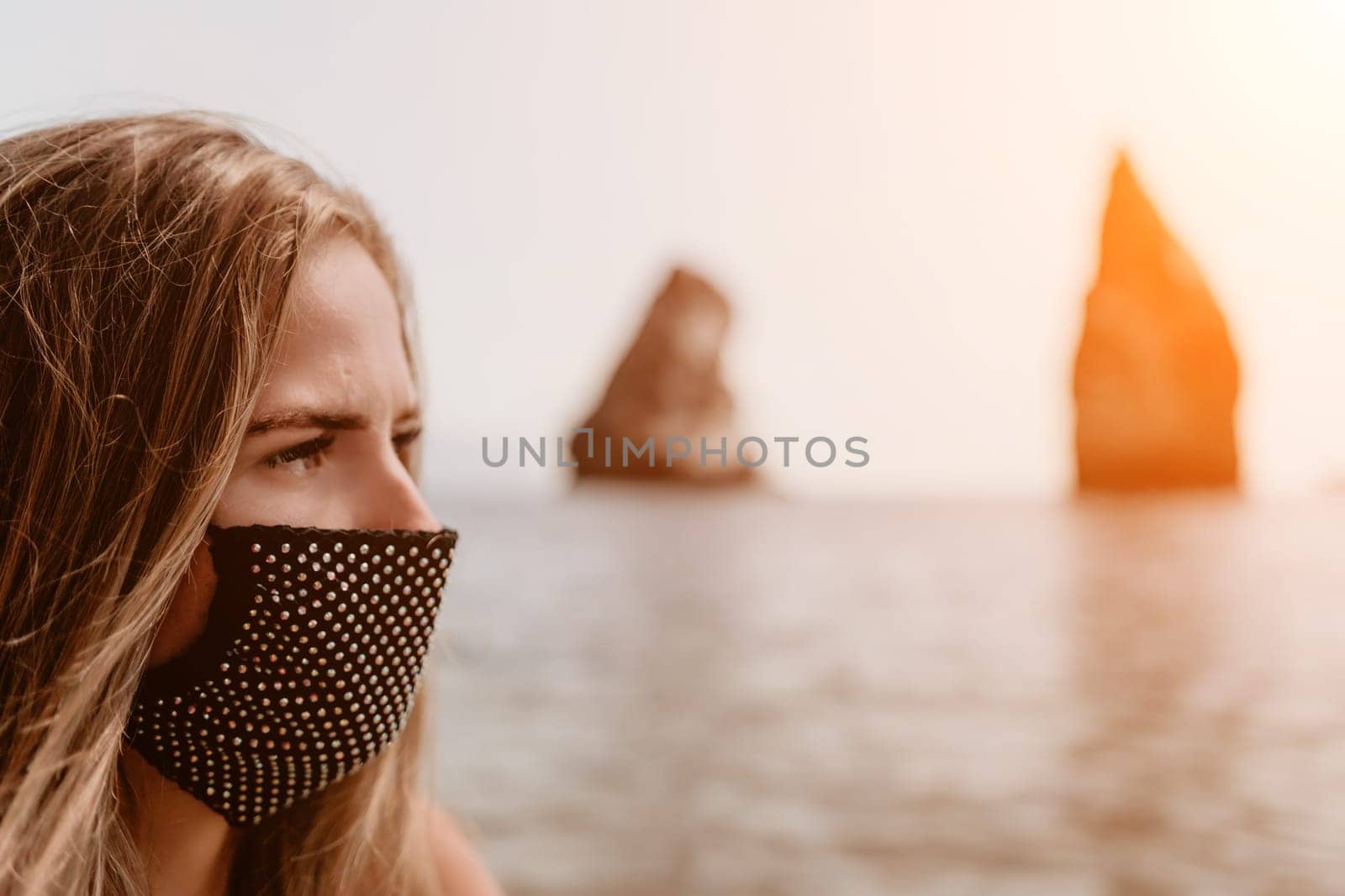 Woman travel sea. Young Happy woman in a long red dress posing on a beach near the sea on background of volcanic rocks, like in Iceland, sharing travel adventure journey