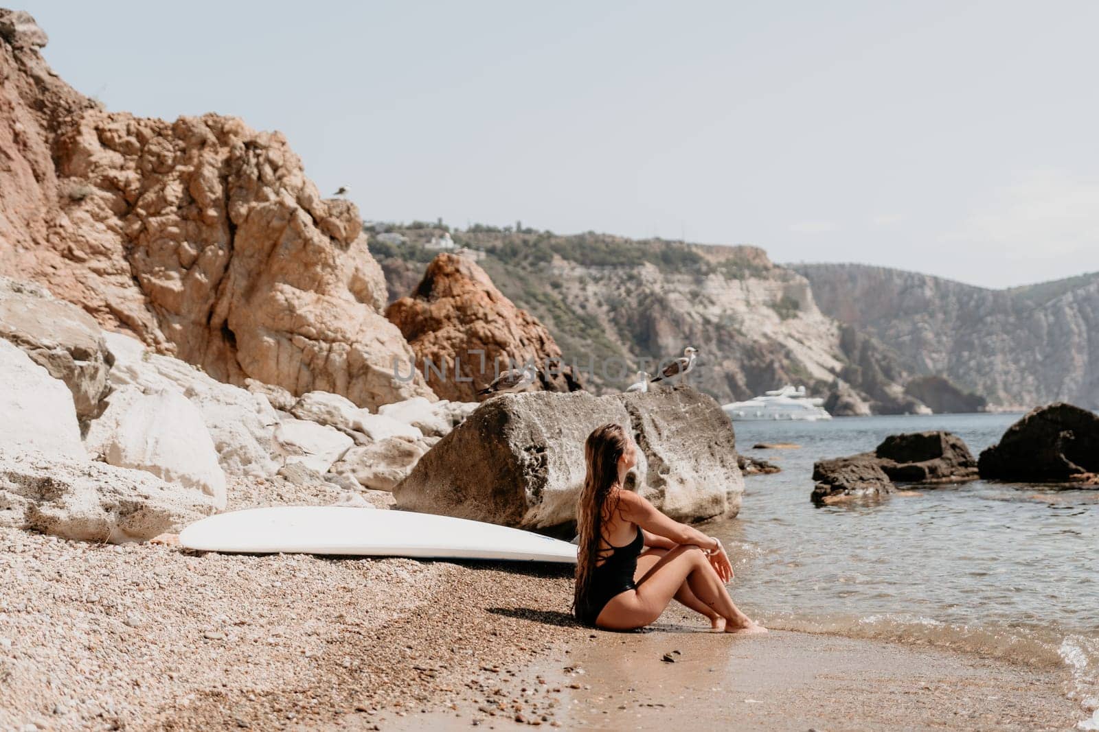 Woman travel sea. Young Happy woman in a long red dress posing on a beach near the sea on background of volcanic rocks, like in Iceland, sharing travel adventure journey