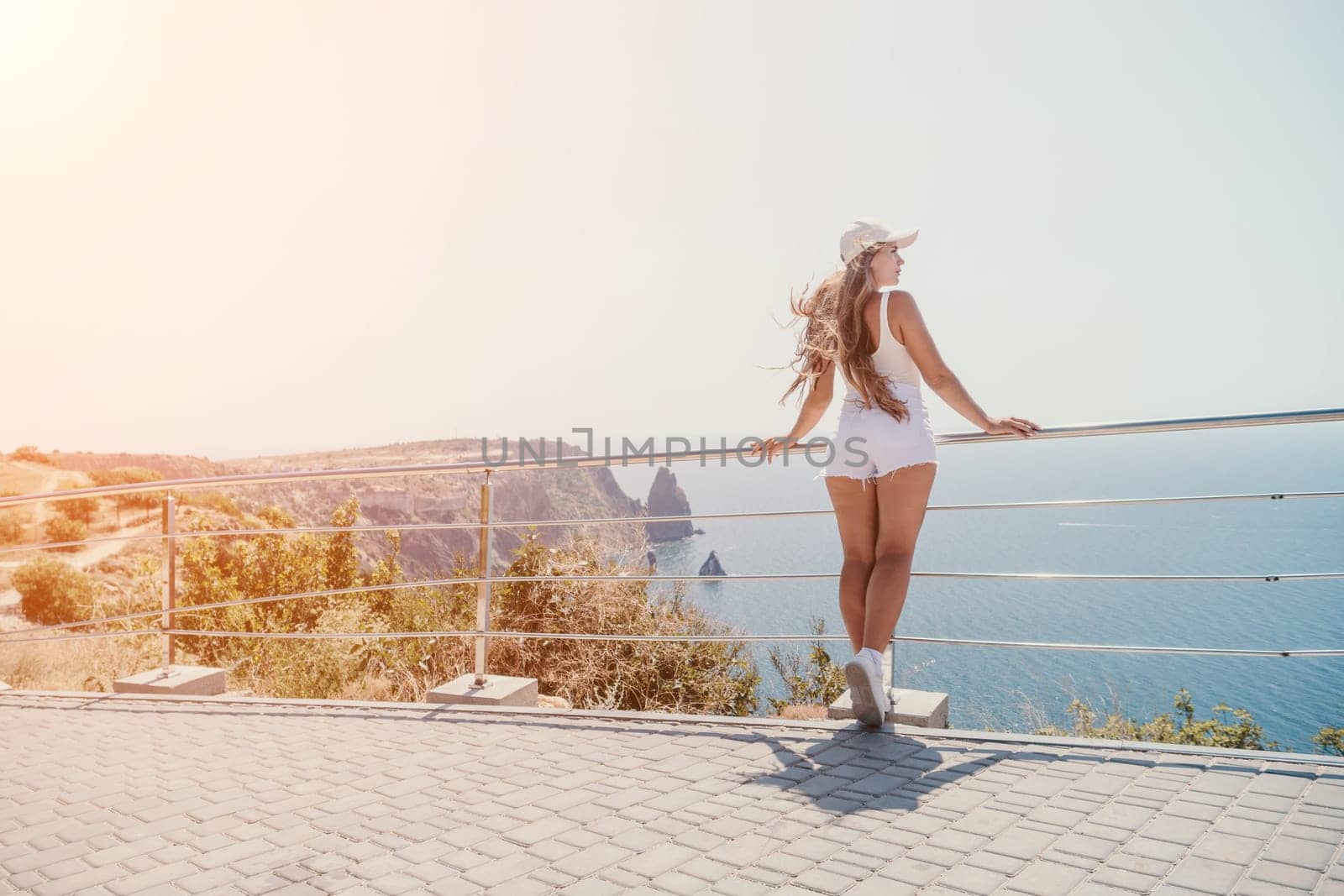 Woman travel sea. Young Happy woman in a long red dress posing on a beach near the sea on background of volcanic rocks, like in Iceland, sharing travel adventure journey