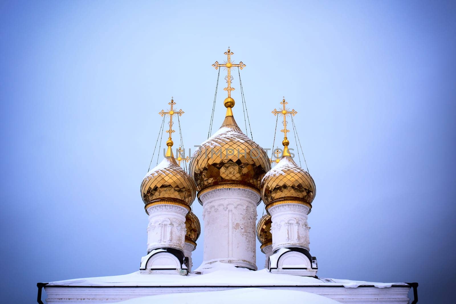 Orthodox church with golden domes and crosses in winter against the blue sky