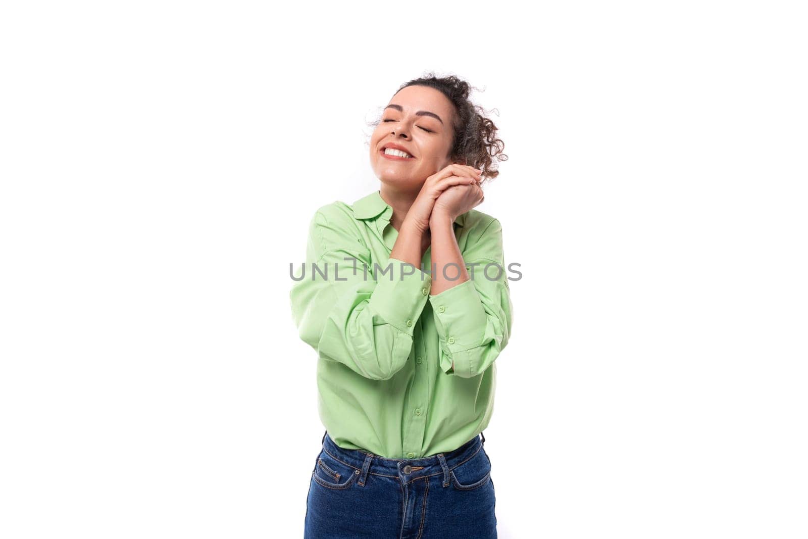 young smiling happy caucasian secretary woman with black curly hair tied in a ponytail on a white background with copy space by TRMK