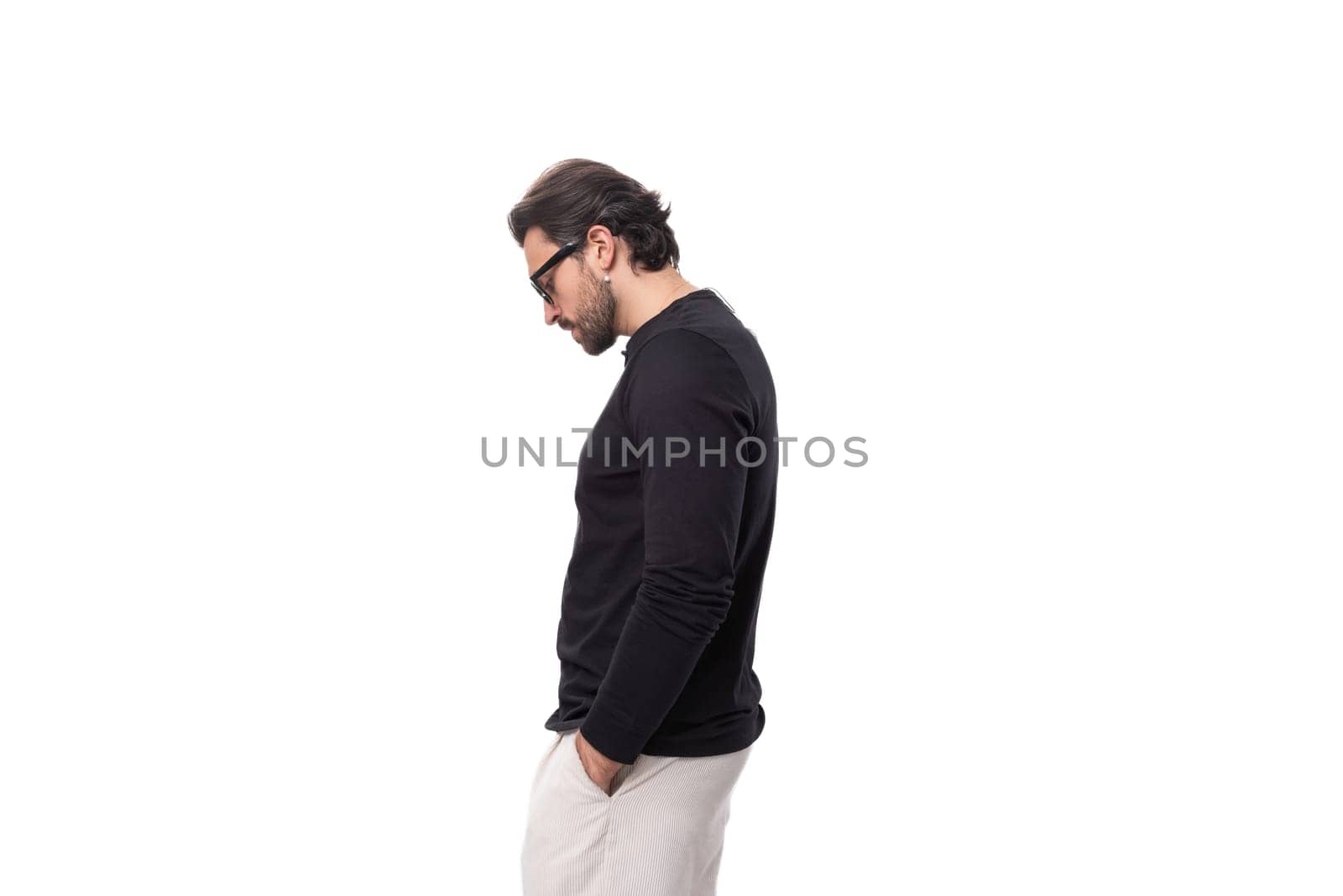 a young brunette man with a black beard and mustache dressed in a black turtleneck stands in profile by TRMK