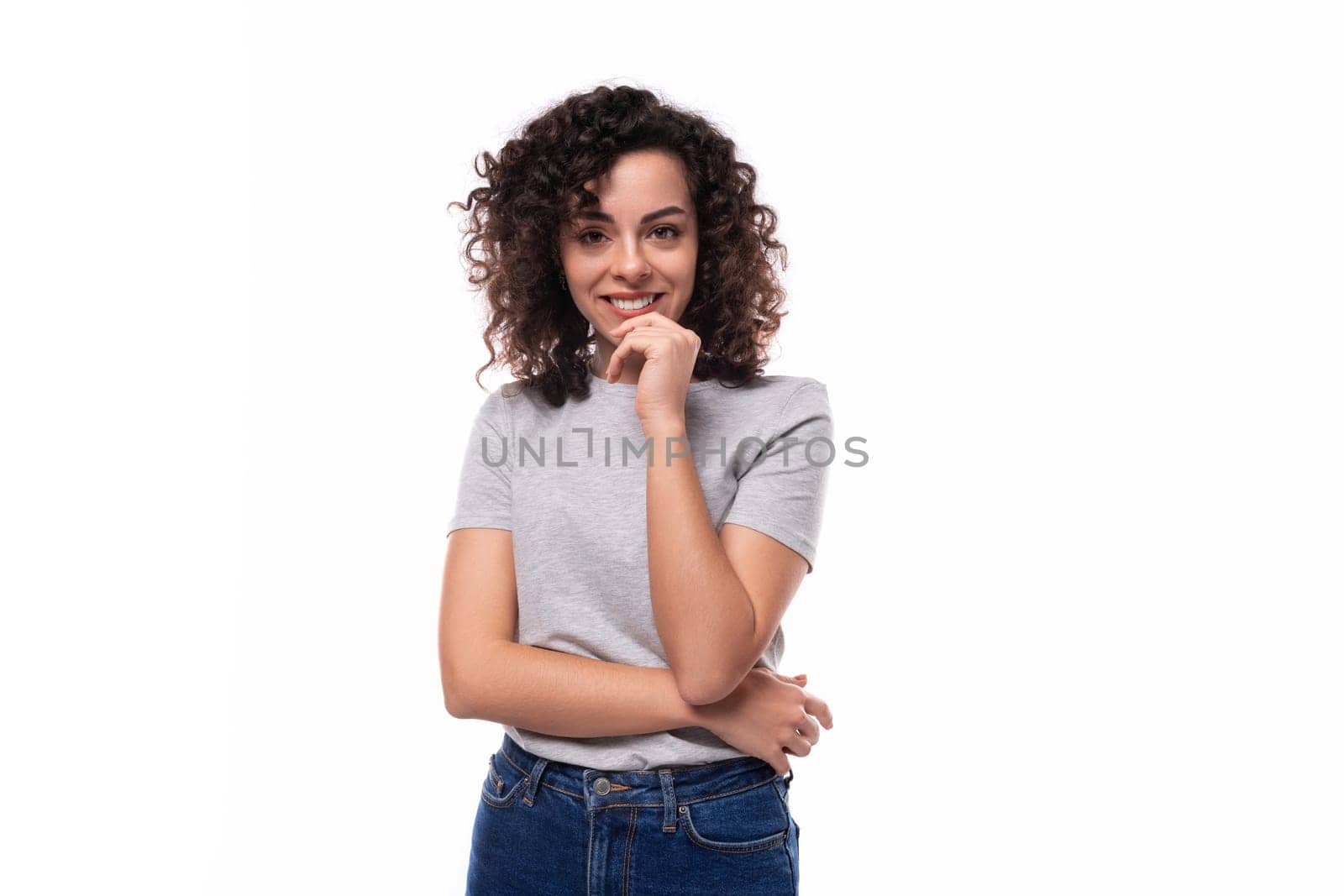 positive confident bright young european slim brunette woman with curly hair style dressed in a gray t-shirt on a white background with copy space.