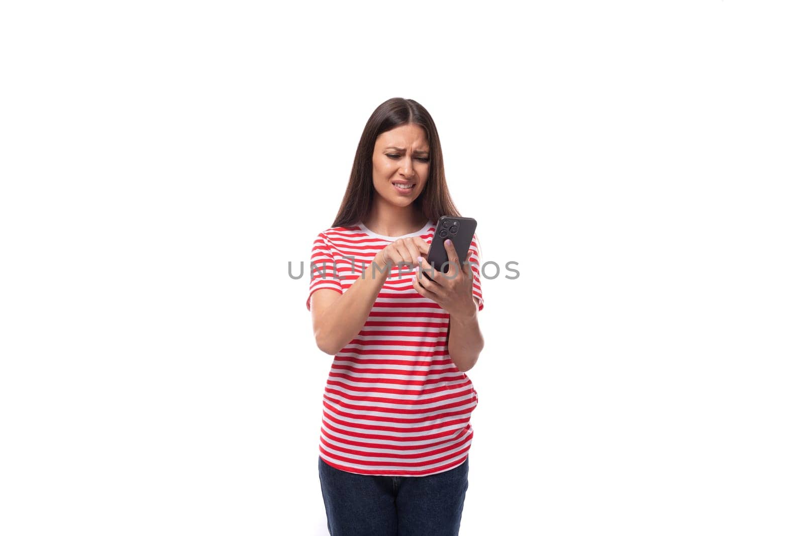 A 35-year-old European lady in a red striped T-shirt uses a mobile phone to communicate in social networks..