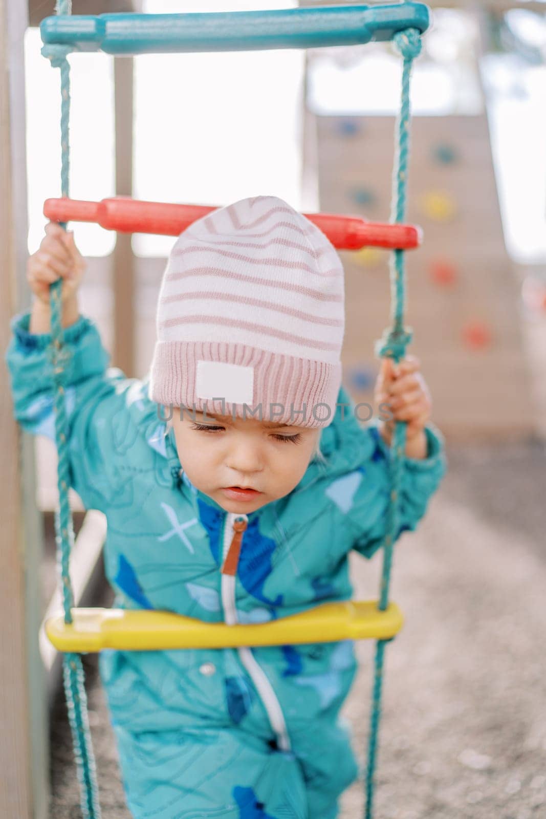 Little girl holding on to a rope ladder and looking down. High quality photo
