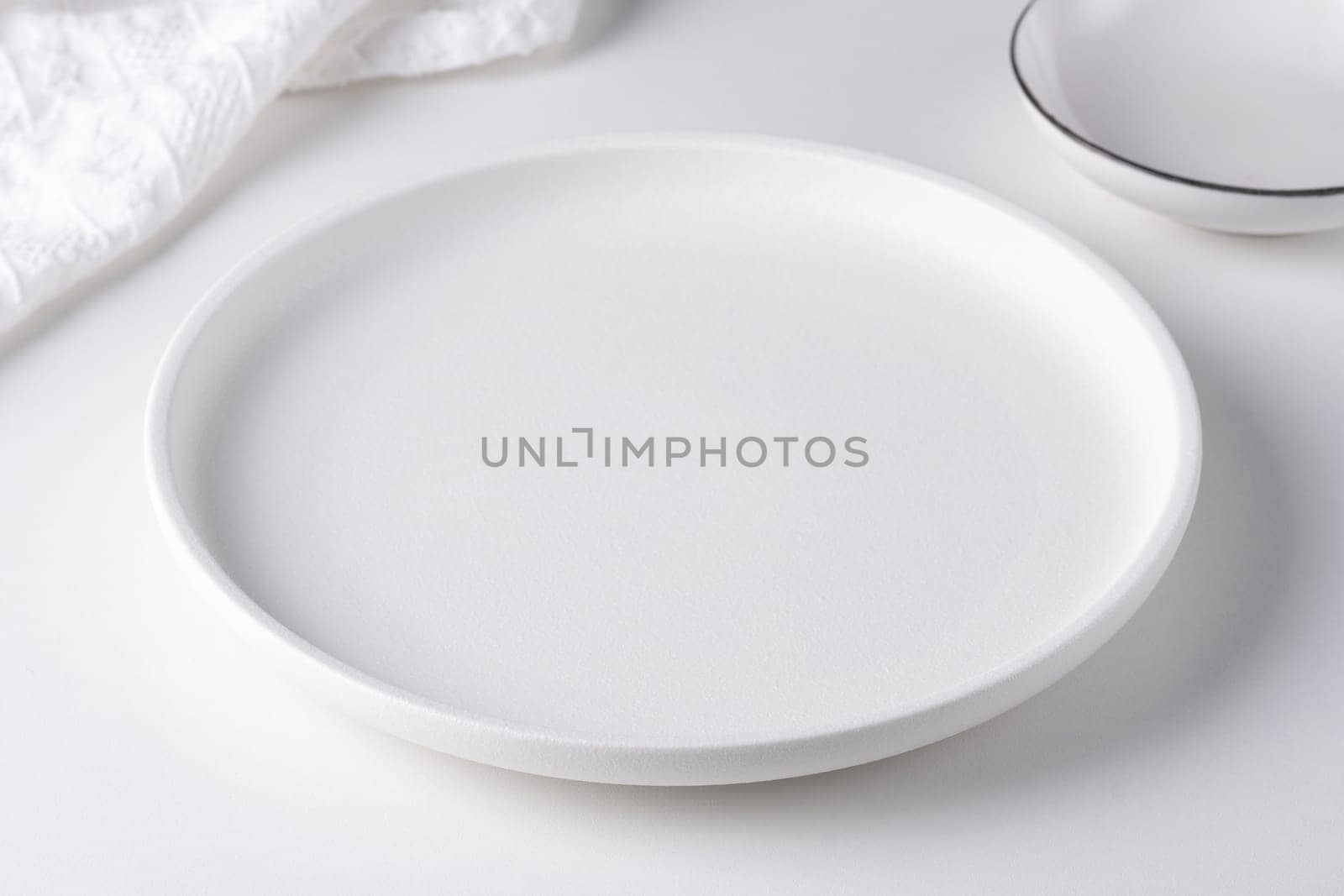 Empty white plate on a white table.