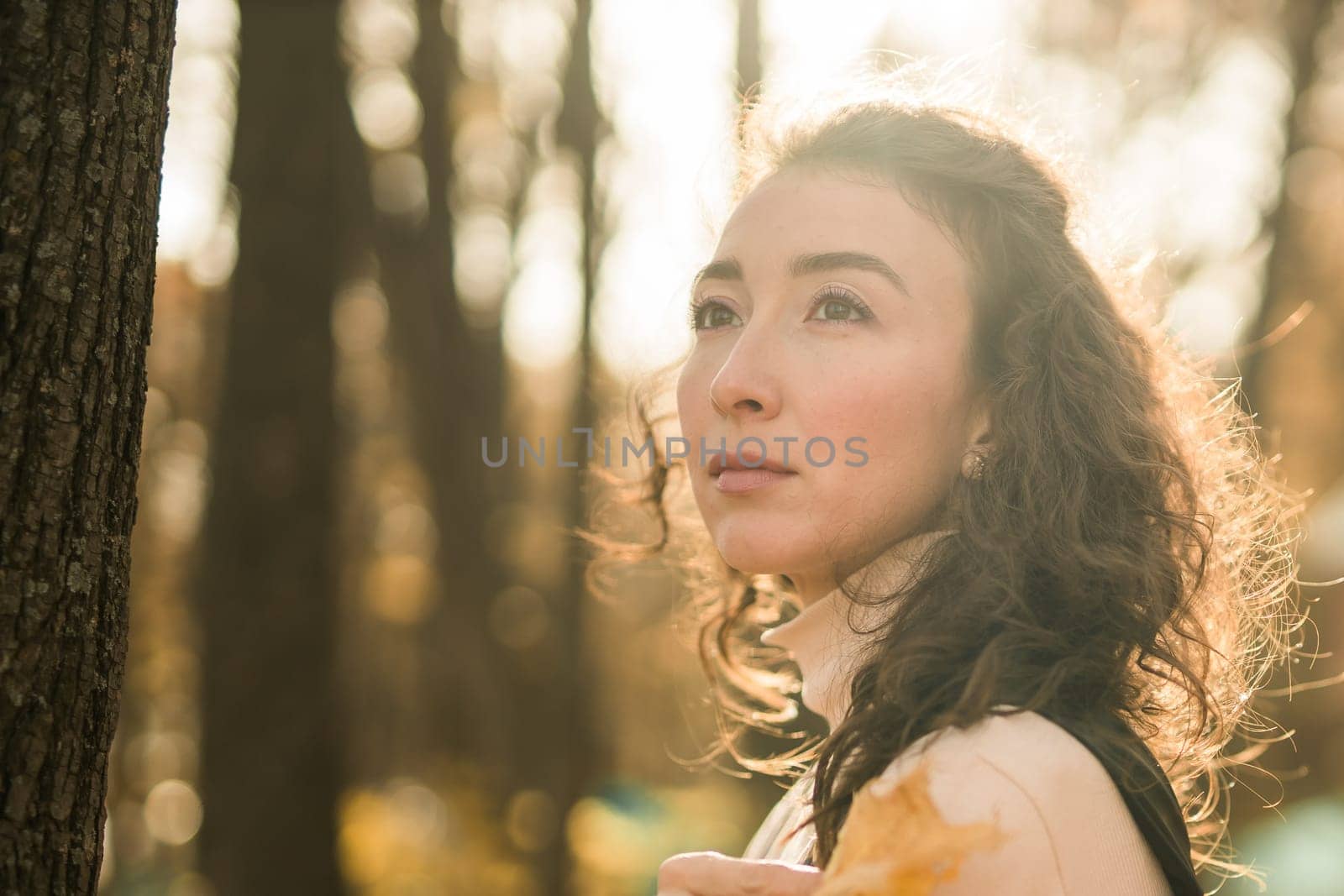 Attractive young woman walking in autumn park, happy mood and fashion style trend and curly long brown hair. Fall season and pretty female portrait. Millennial generation