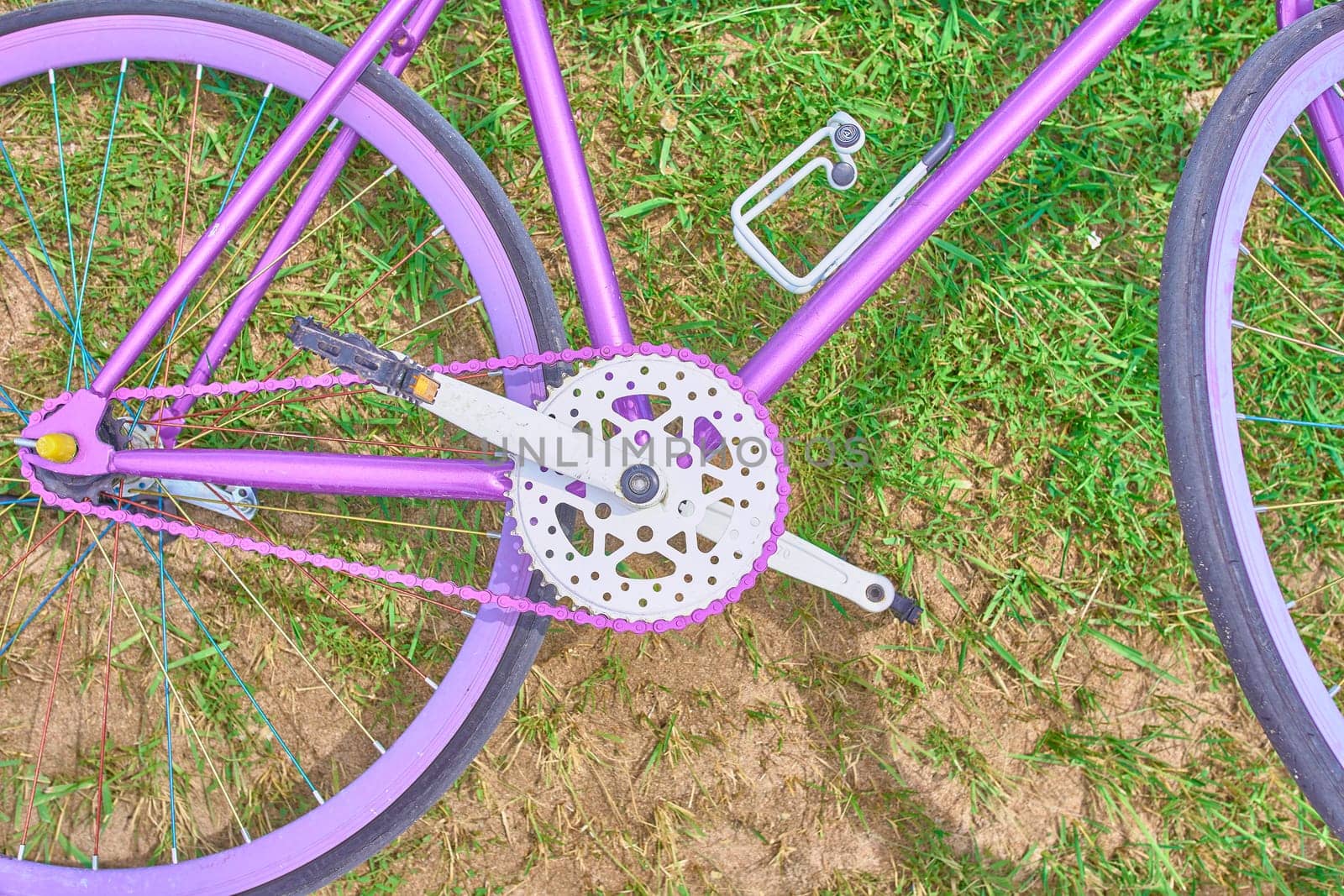 Bright pink bike lying on the grass with sand on a Sunny day