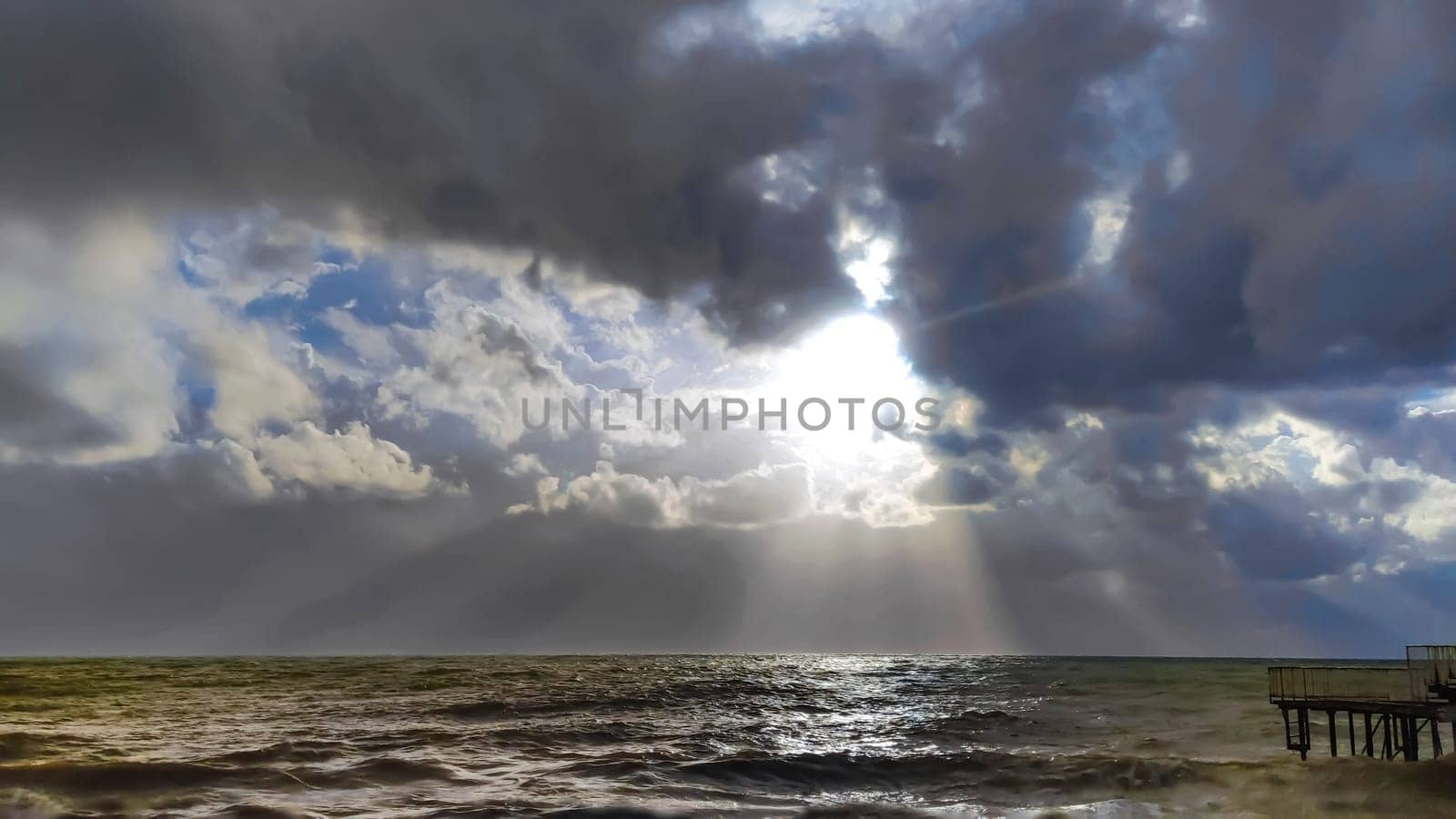 Landscape of stormy sea and clouds with gaps sun's rays, view from shore by Laguna781