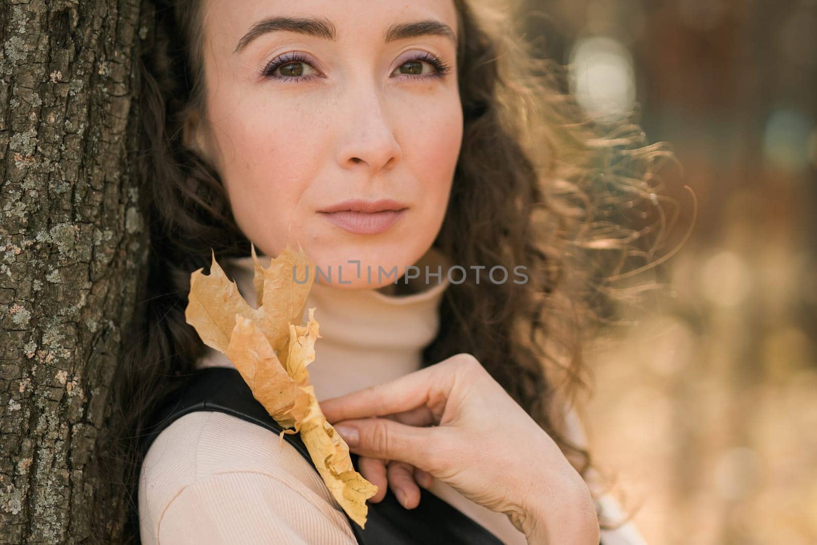 Attractive young woman walking in autumn park, happy mood and fashion style trend and curly long brown hair. Fall season and pretty female portrait. Millennial generation