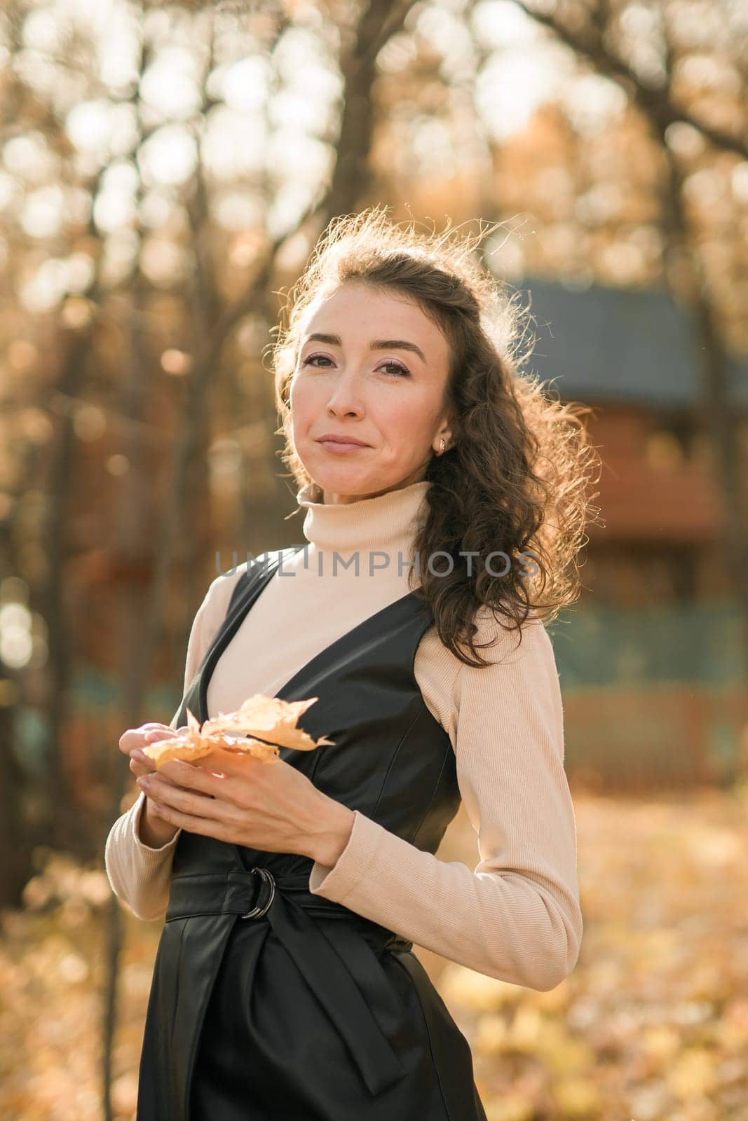 Attractive young woman walking in autumn park, happy mood and fashion style trend and curly long brown hair. Fall season and pretty female portrait copy space. Millennial generation concept by Satura86