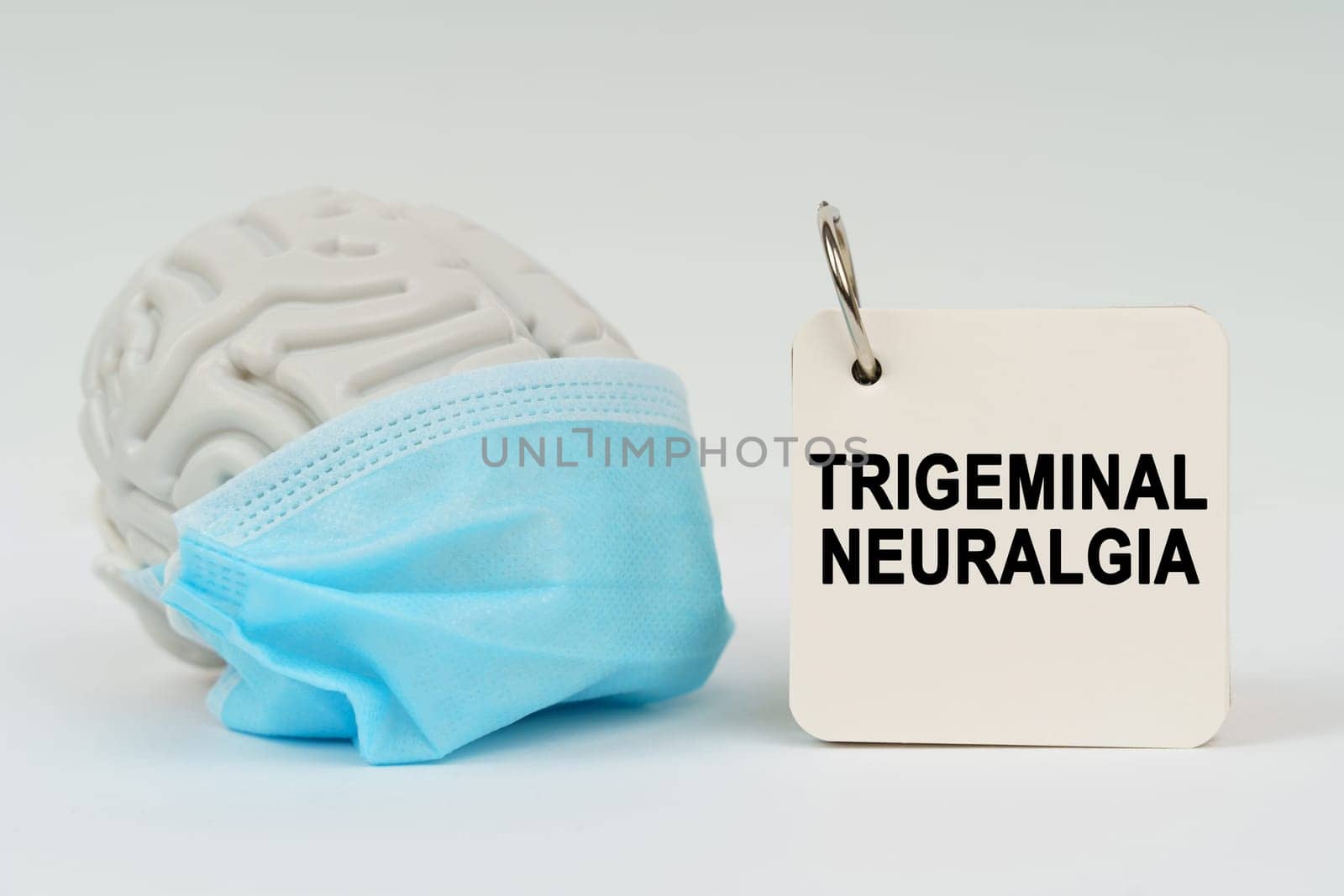 Medical concept. On a white surface there is a brain with a blue mask and a notepad with the inscription - Trigeminal neuralgia