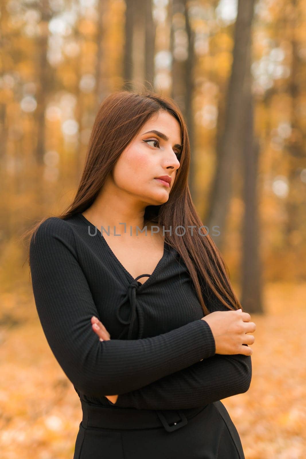 Beautiful indian woman generation z relaxing and feeling nature at autumn park in fall season. Diversity and gen z youth.