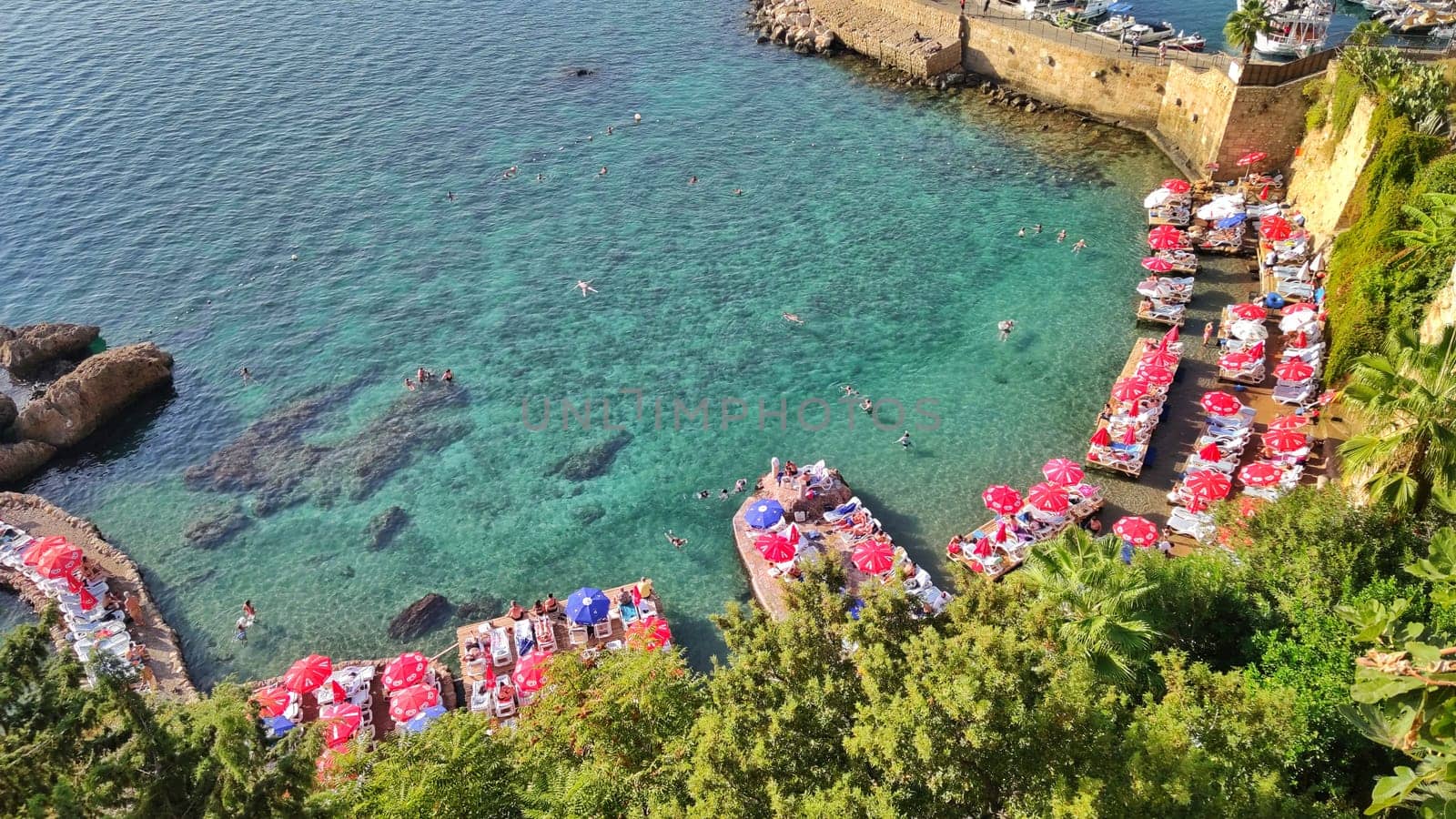 Turkey, Antalya, Kaleichi, October 23, 2023, people swim and sunbathe on well-maintained paid beach in beautiful blue lagoon, top view