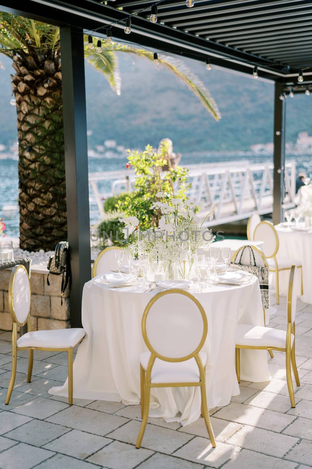 Restaurant terrace by the sea with a set round table with a bouquet of flowers. High quality photo