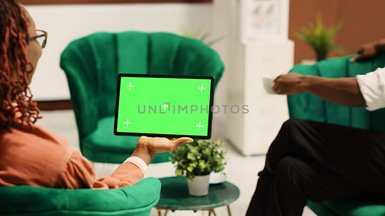Tourists in hotel lobby being assisted by manager, holding chroma key green screen mock up tablet in landscape mode. Resort administrator helping guests during check in process