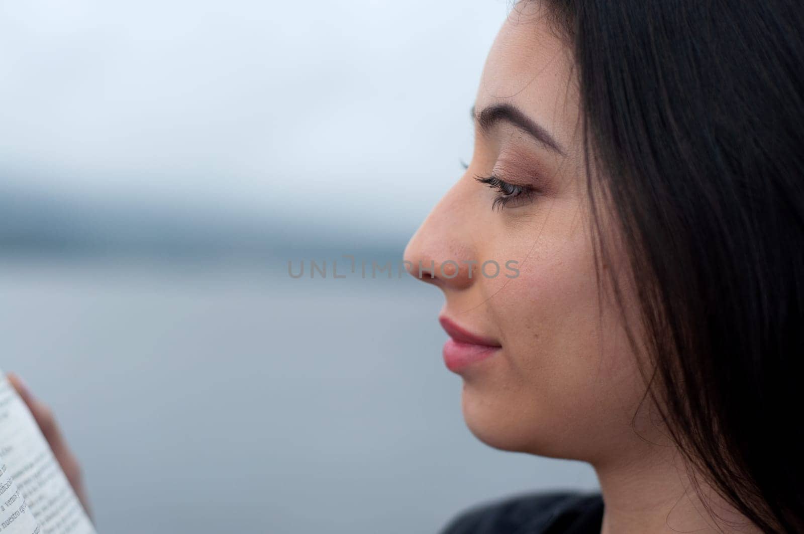 close-up copyspace of a venezuelan girl reading a book next to a lake. book day. High quality photo
