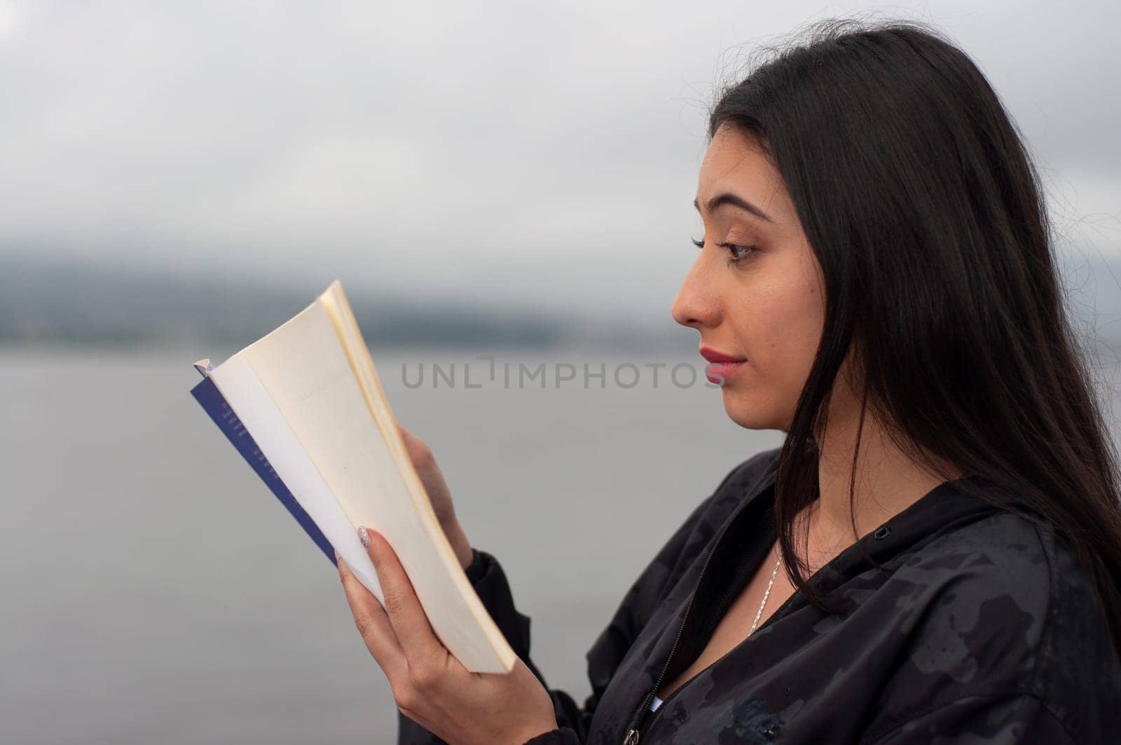 attractive young woman in a black shirt from colombia reading a novel with an expression of incomprehension. book day by Raulmartin