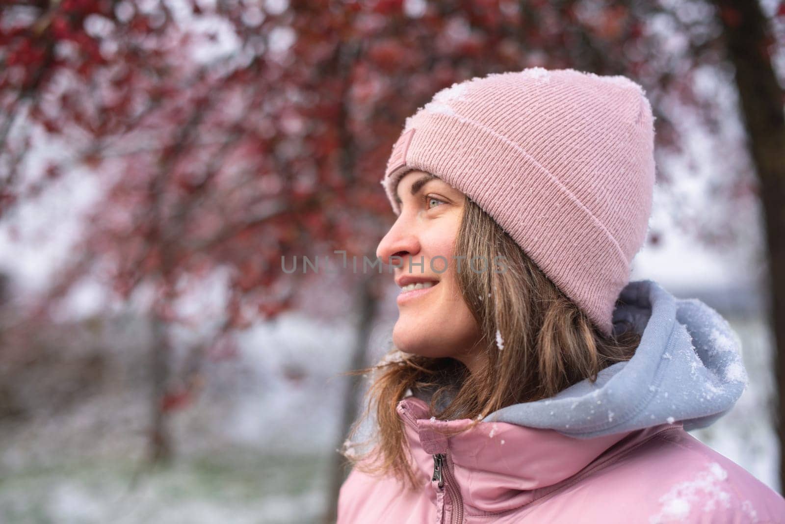 Winter Elegance: Portrait of a Beautiful Girl in a Snowy European Village. Winter lifestyle portrait of cheerful pretty girl. Smiling and having fun in the snow park. Snowflakes falling down. Christmas Radiance: Capturing Winter Elegance in the Snowy Ambiance of a European Village by Andrii_Ko