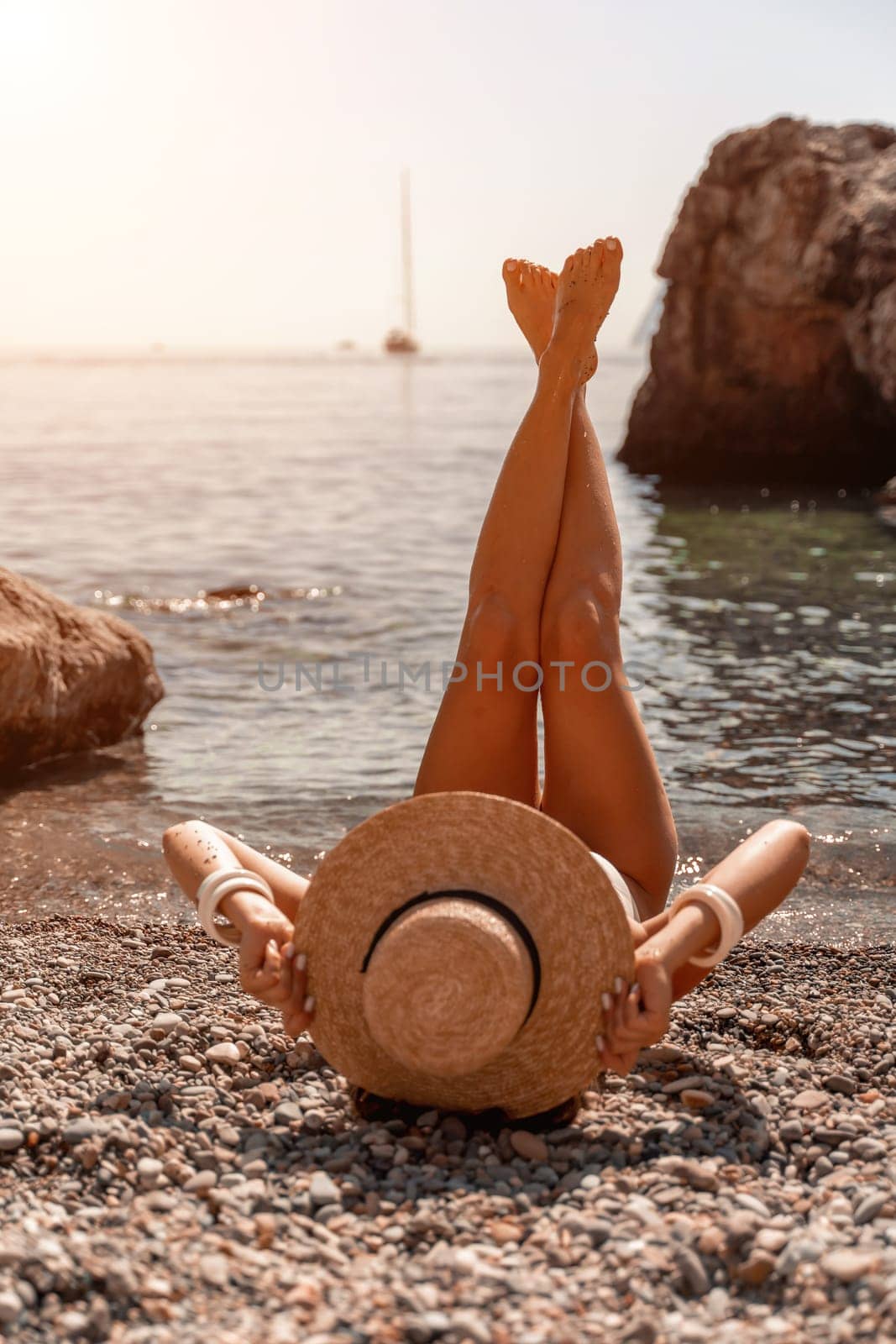 woman sea travel Tanned middle-aged woman with long hair and a white bathing suit. He sits on the seashore in a large sun hat with his back and looks at the sea. by Matiunina