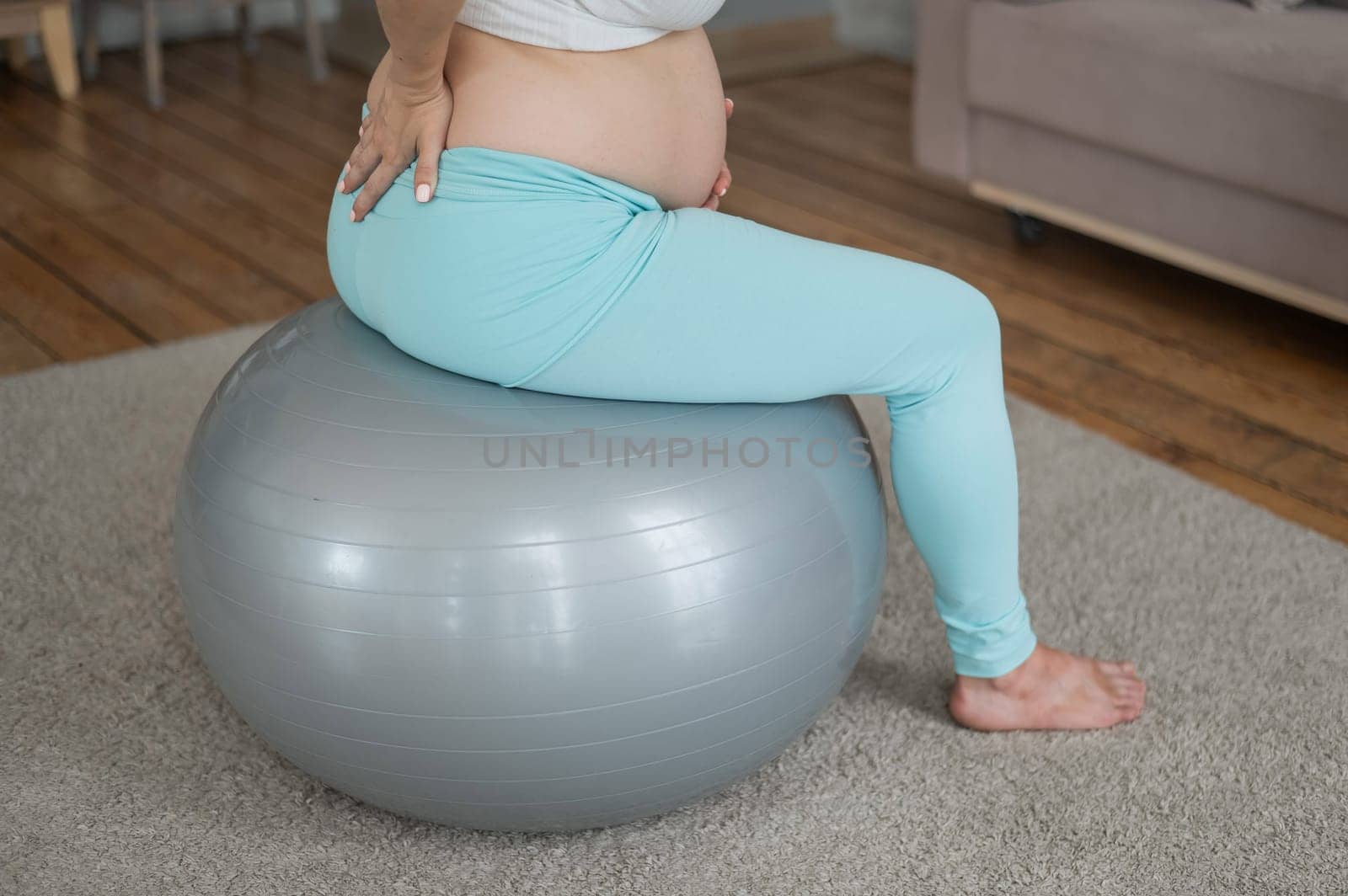 Caucasian pregnant woman suffers from back pain. Fitball training during pregnancy. by mrwed54
