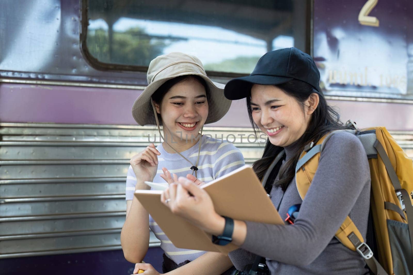 Two female friend talking about trip on their way to train. traveling concept by itchaznong