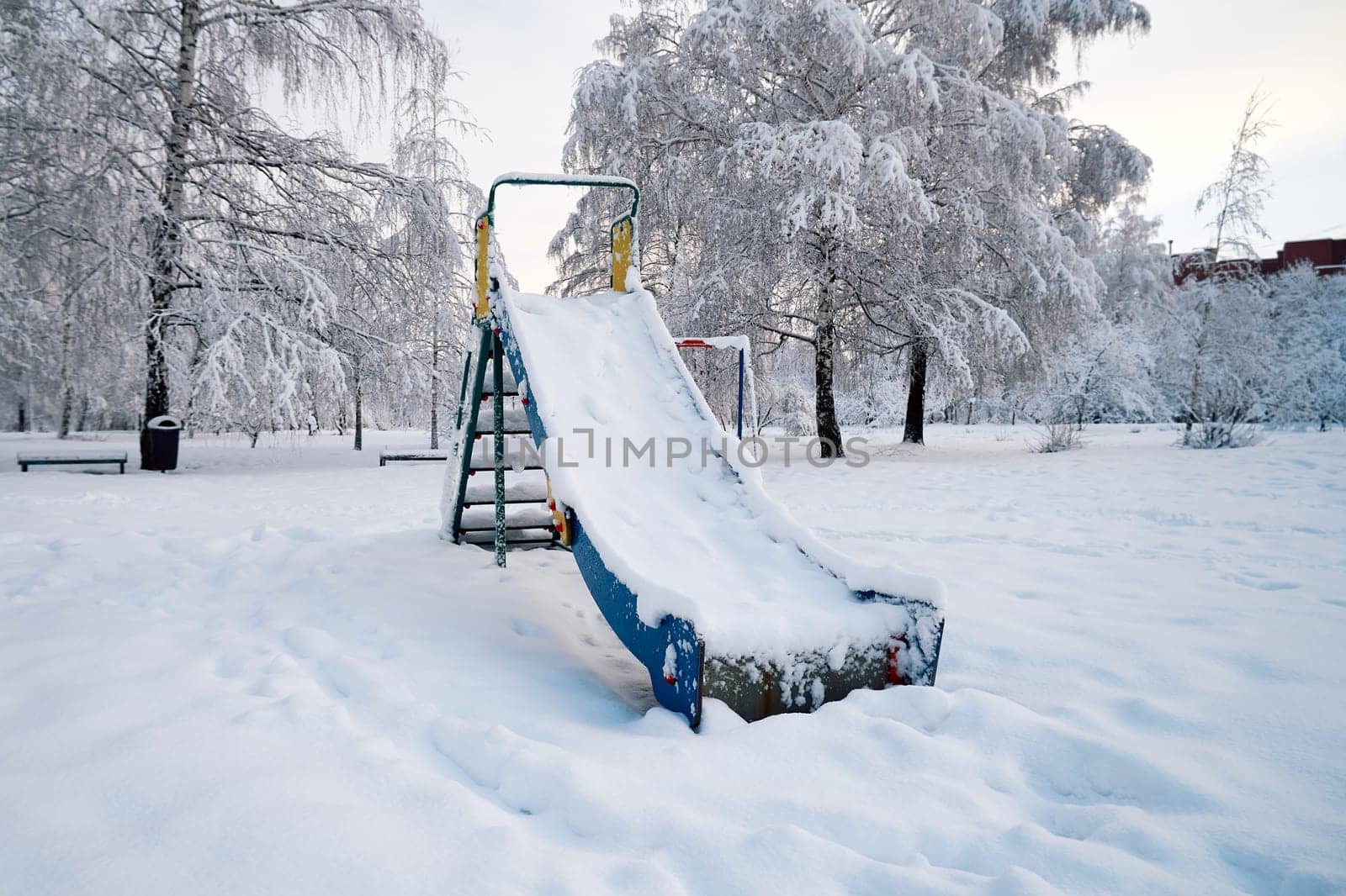 Children's slide in the park covered with snow