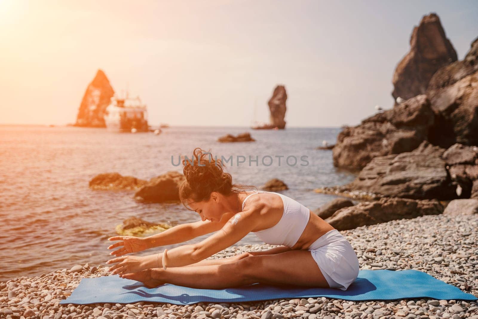 Woman sea yoga. Two Happy women meditating in yoga pose on the beach, ocean and rock mountains. Motivation and inspirational fit and exercising. Healthy lifestyle outdoors in nature, fitness concept. by panophotograph