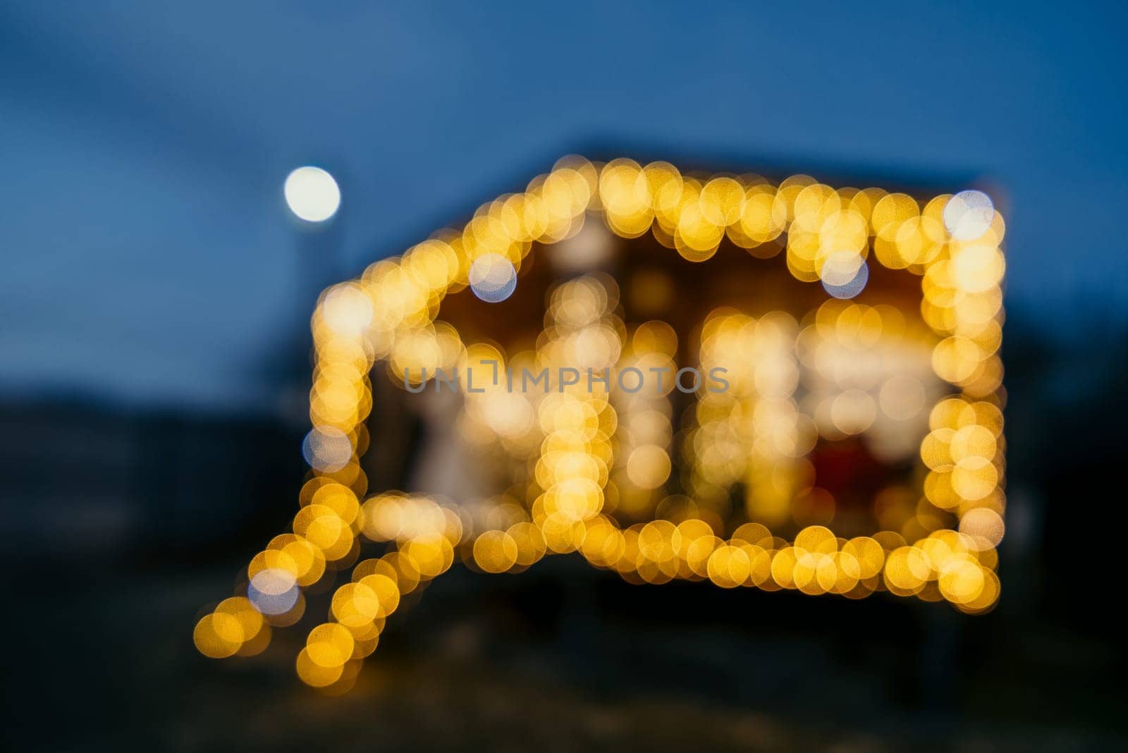 Abstract defocused bright Christmas lights on wooden house, creating decorative illumination in evening scene by panophotograph