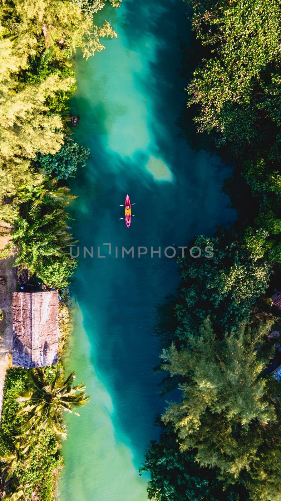 Couple men and women peddling in a kayak during the afternoon at sunset, People in a Kayak at a river klong of a tropical Island Koh Chang Thailand during sunset in the rainforest jungle