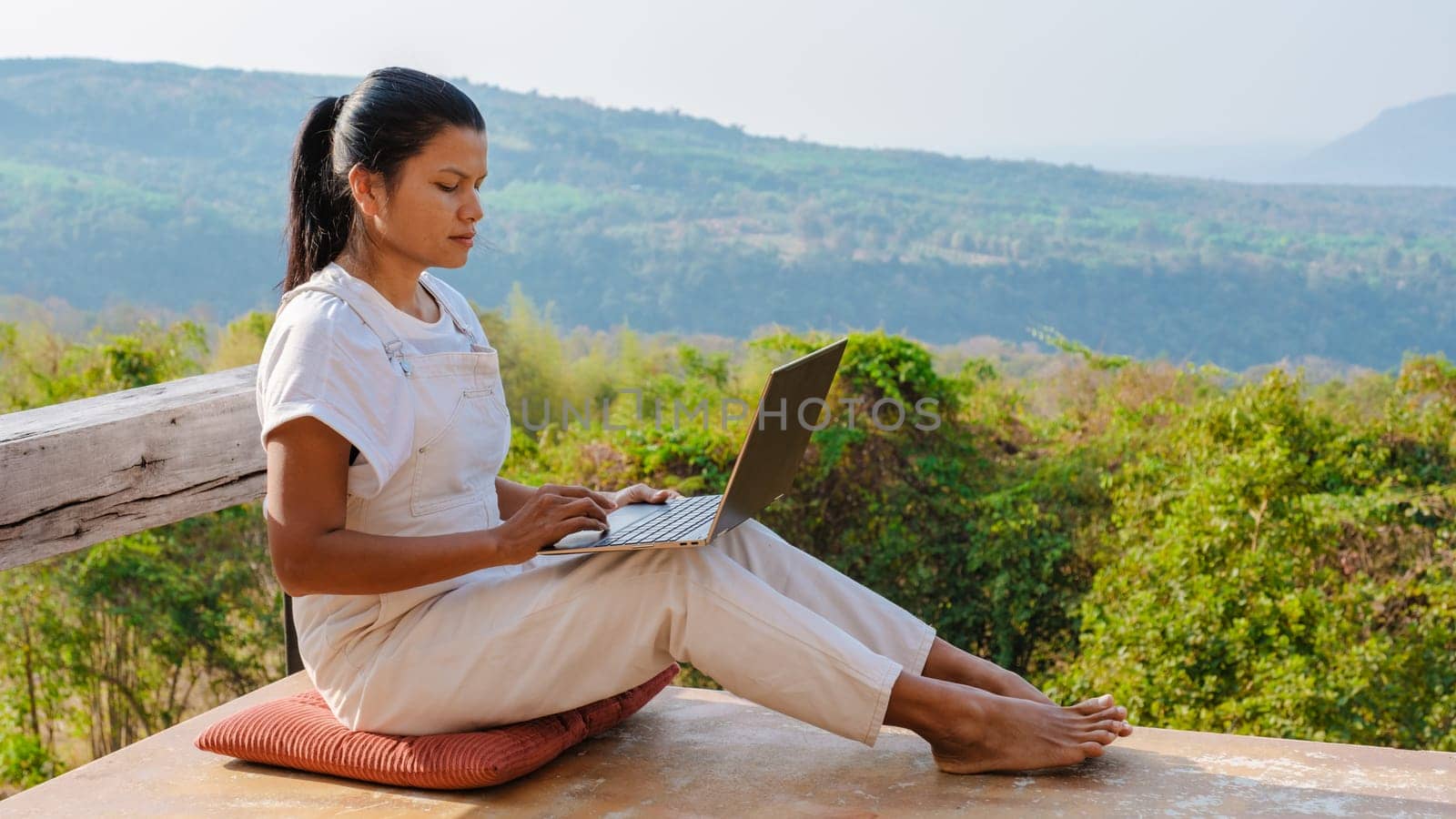 Young business woman working at the computer laptop at sunset on the top of the mountain by fokkebok