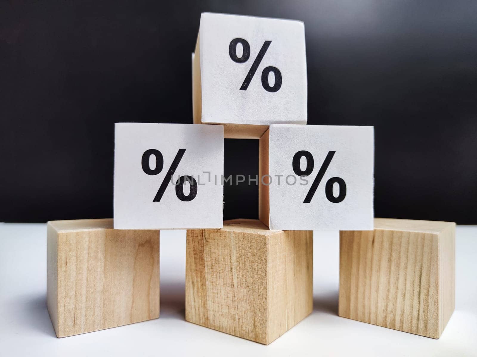 Wooden cubes with arrows and percentages on a black background. Stages of action and goal achievement. Planning. Business actions. Receiving income and profit by keleny