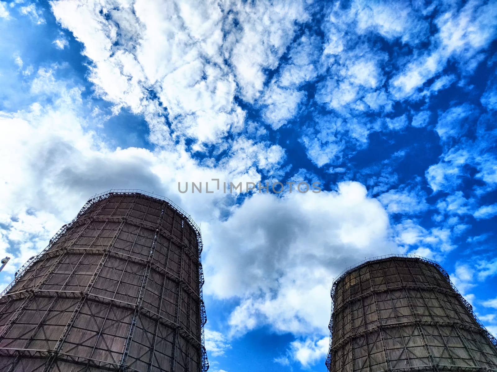 Big tower of CHPP close-up. White steam from wide pipe of CHP and blue sky. Industrial background. Huge pipes of thermal power plant produce steam for electric power. Strategically important object