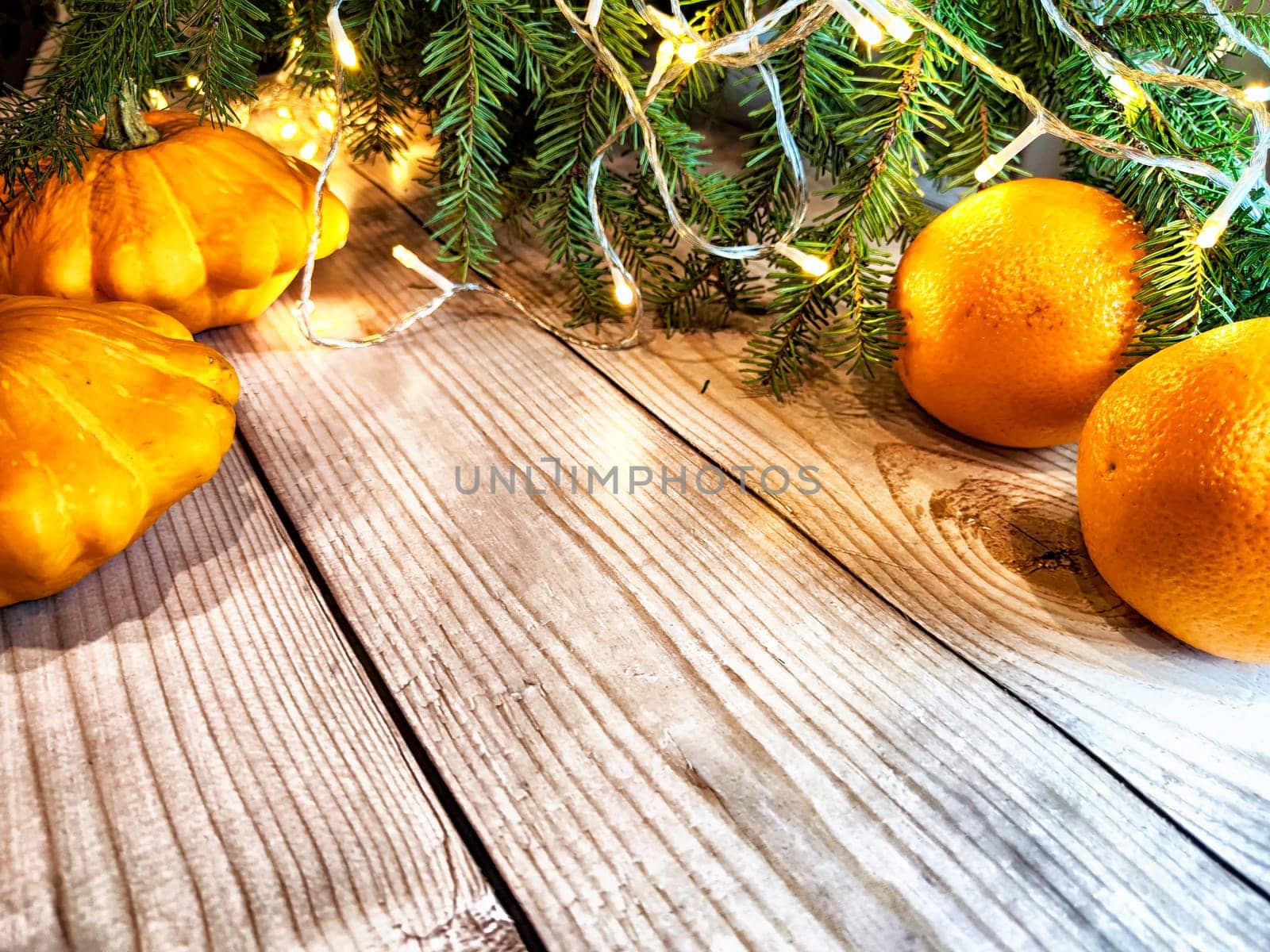 Festive decoration with bouquet and branches of spruce, bright glowing garlands, oranges on wooden background. Decor for Christmas and New Year. Abstract texture, frame, place for text and copy space