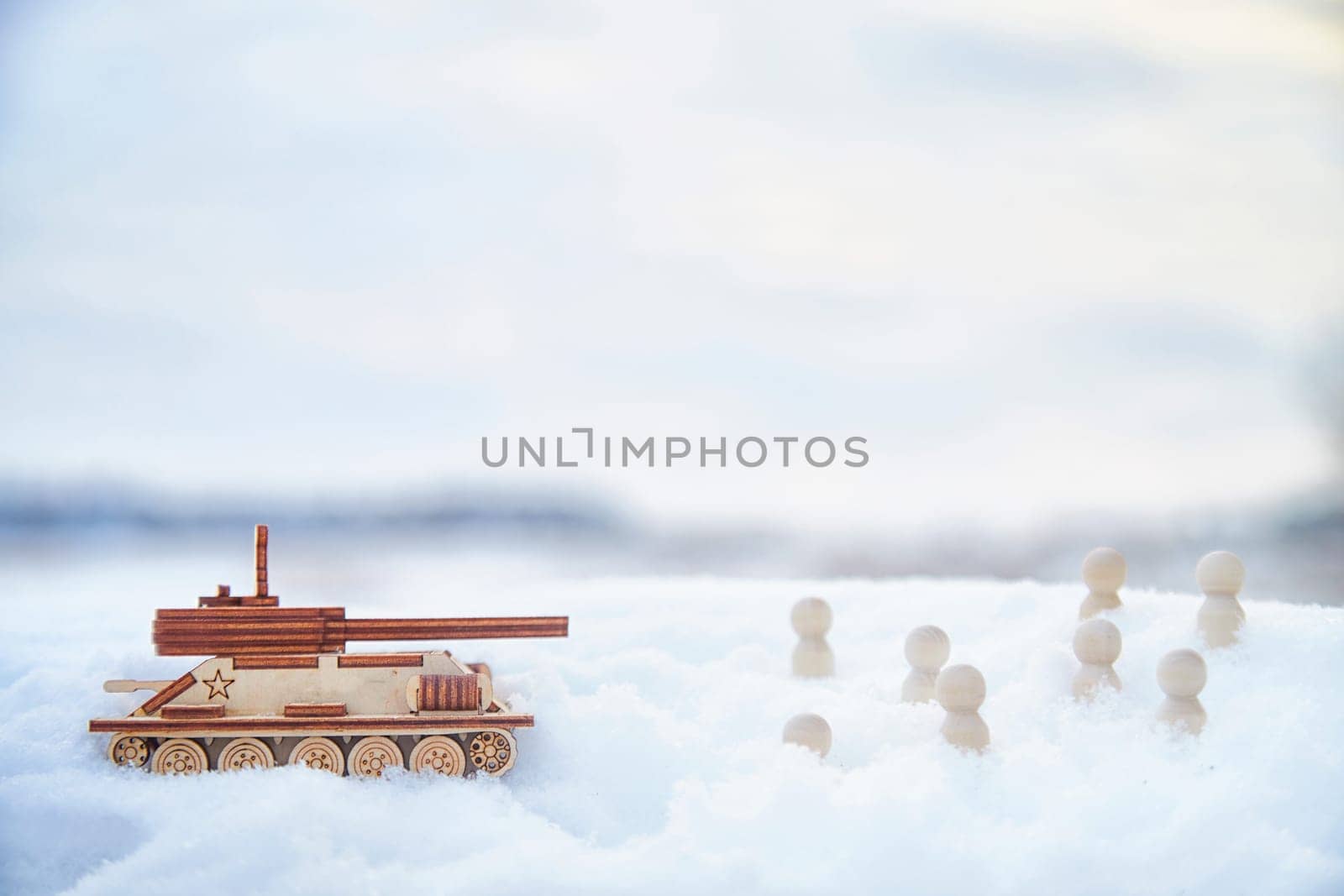 Wooden toy Russian tank T-34 and little men in the snow. Russia and Ukraine are at war in winter. Encirclement, retreat, attack, victory