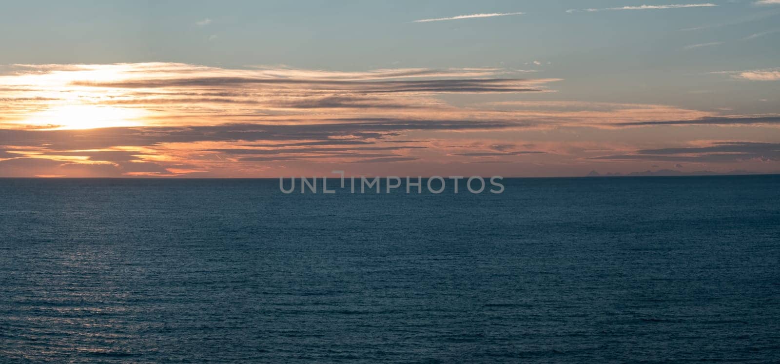 Peaceful ocean with vivid sunset and reflective clouds.