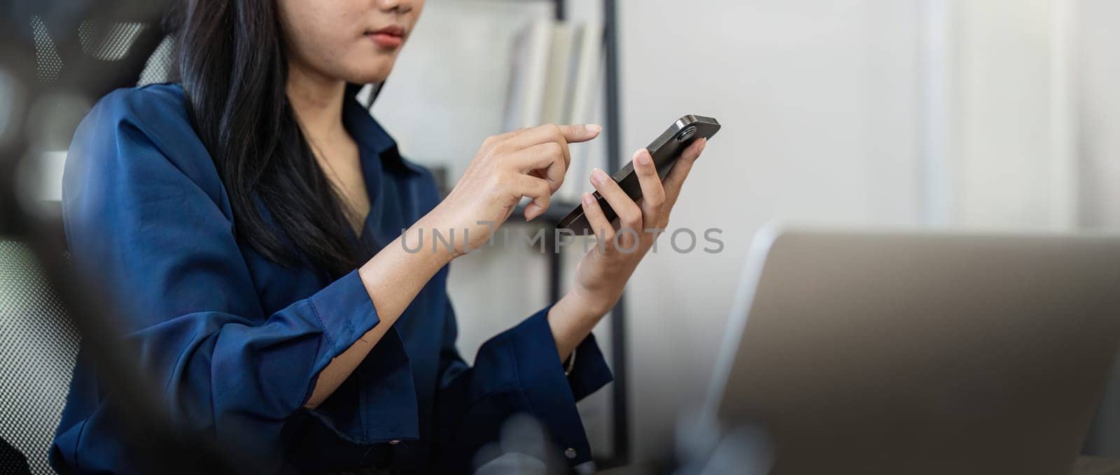 Young business woman on the phone at office. Business woman texting on the phone and working on laptop. Pretty young business woman sitting on workplace by nateemee