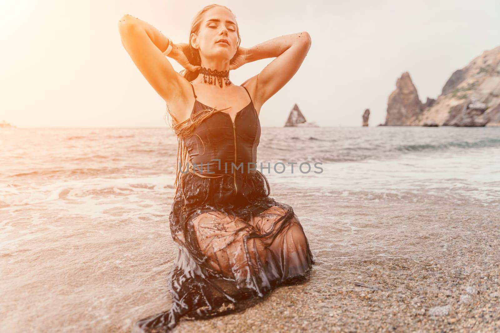 Woman travel sea. Young Happy woman in a long red dress posing on a beach near the sea on background of volcanic rocks, like in Iceland, sharing travel adventure journey