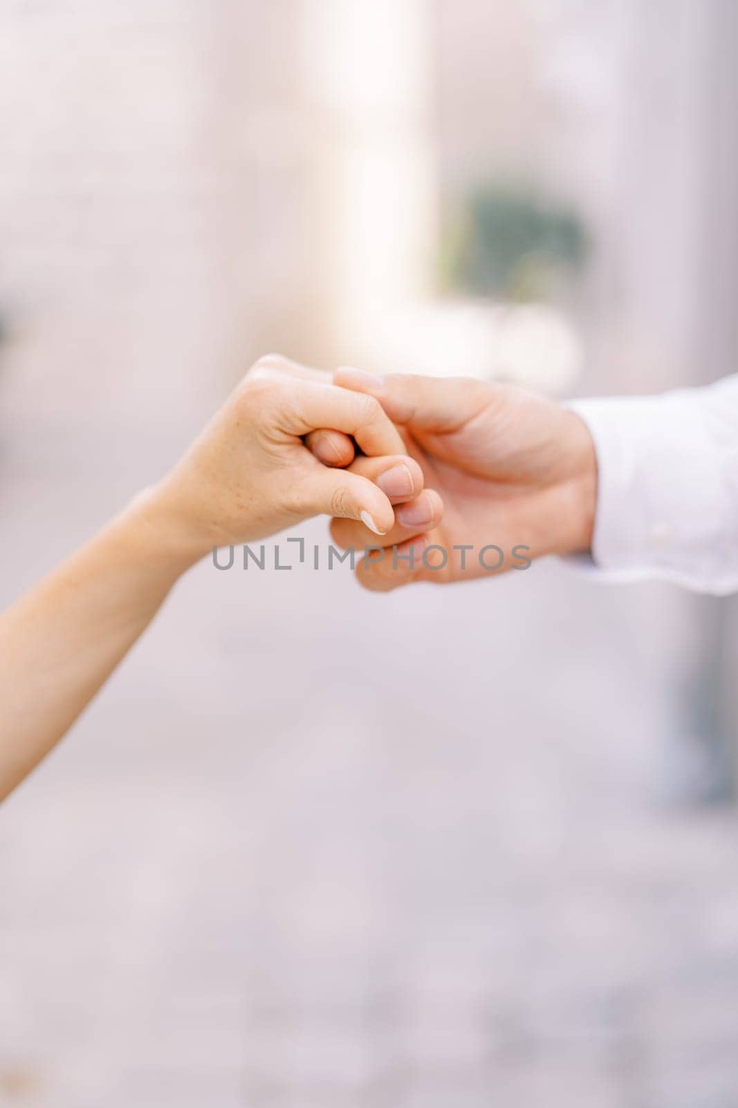 Groom holds bride hand in his own. Cropped. Faceless by Nadtochiy