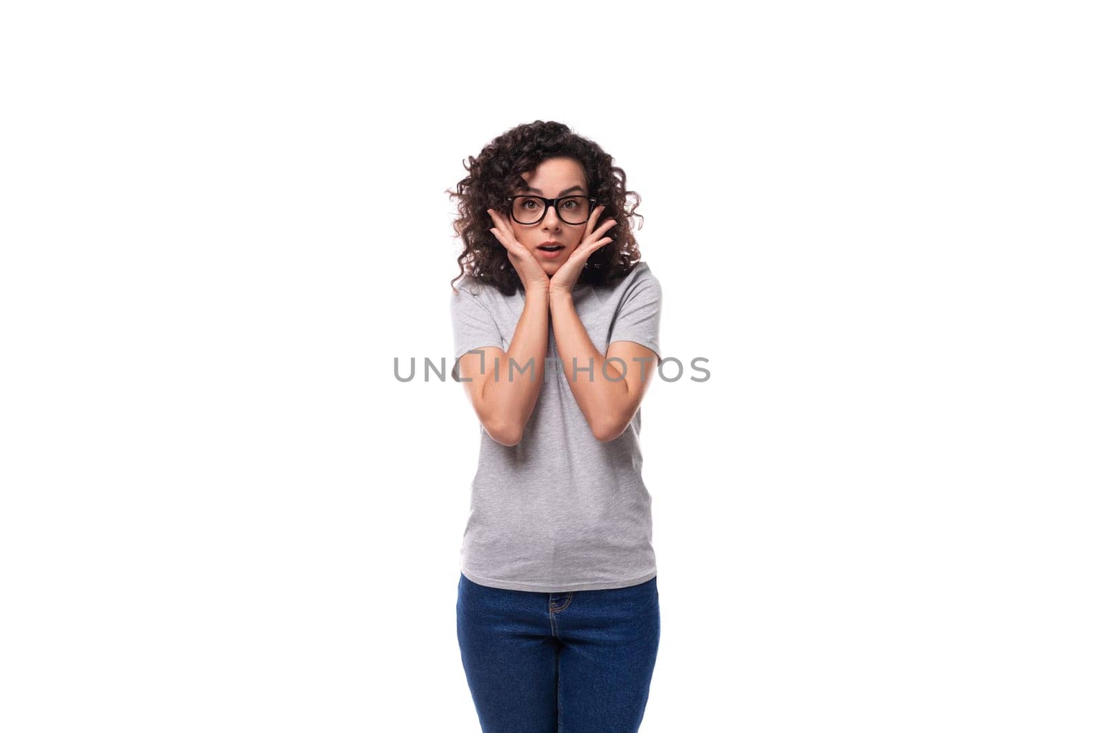 smart young curly brunette woman with glasses for vision in a gray t-shirt on a white background with copy space.
