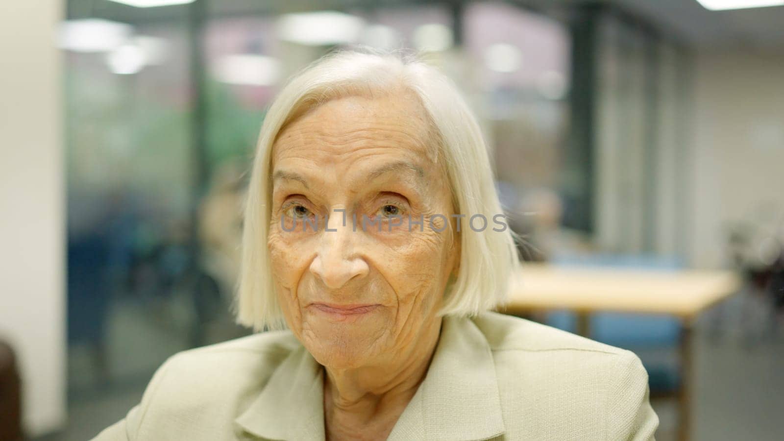 Close-up picture of a senior woman looking to the camera and smiling in a nursing home