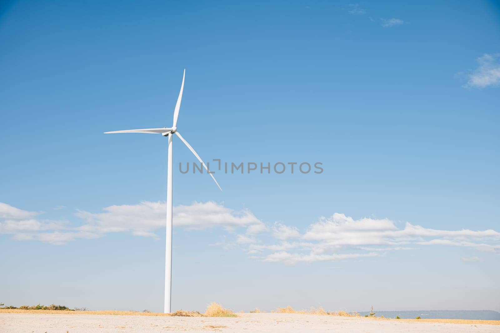 On a mountain windmill farm turbines harness nature's wind for clean energy. Modern innovation in wind technology drives sustainable development under the expansive blue sky.