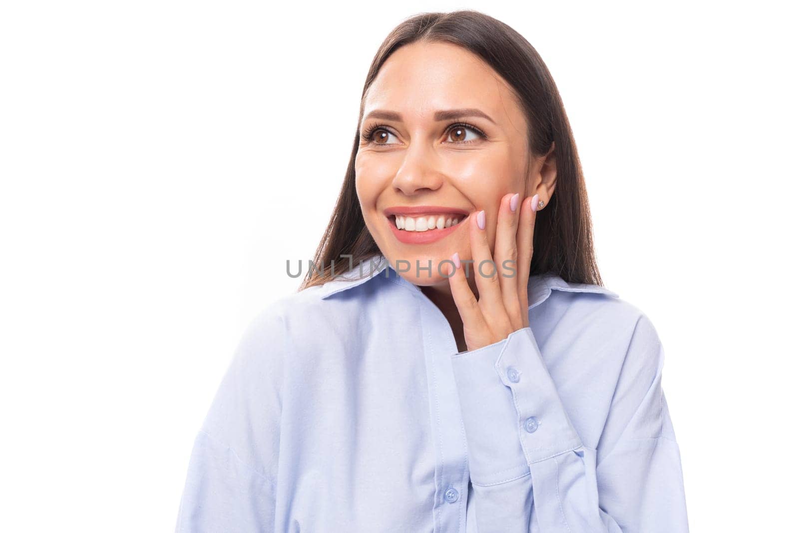 close-up of a young slender beautiful European brunette business woman with light makeup in a light blue shirt.