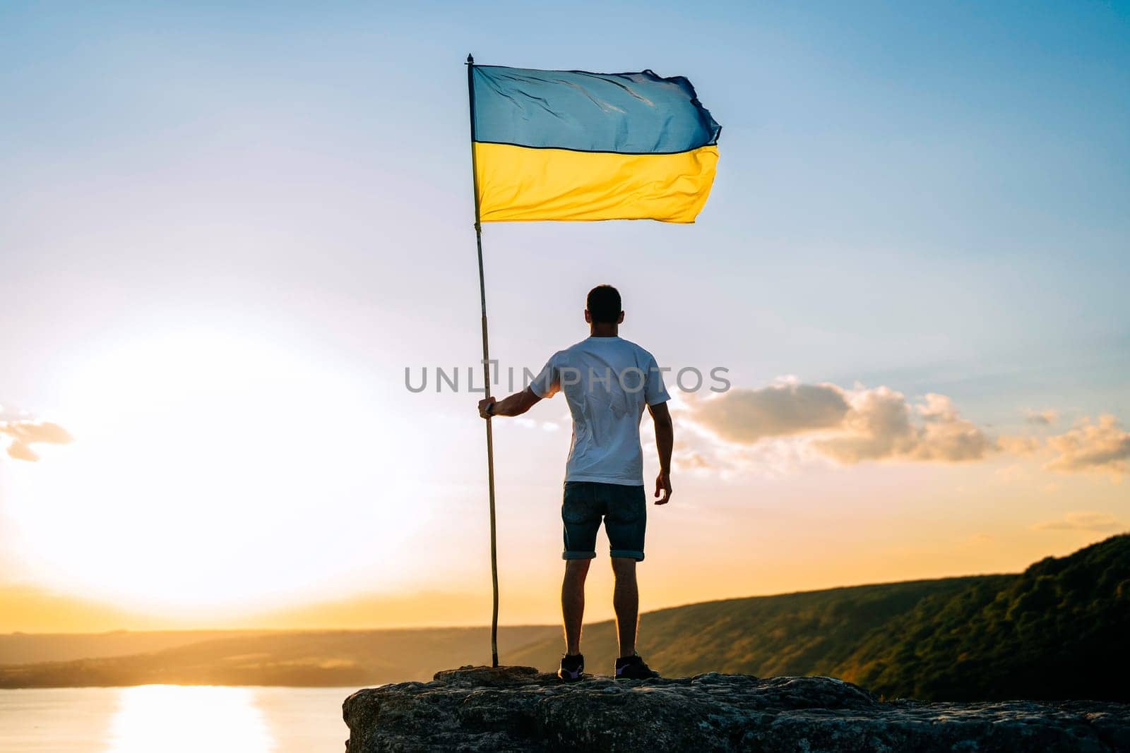 Ukrainian man with national flag on summer sky, high rock, wide river Dniester by kristina_kokhanova